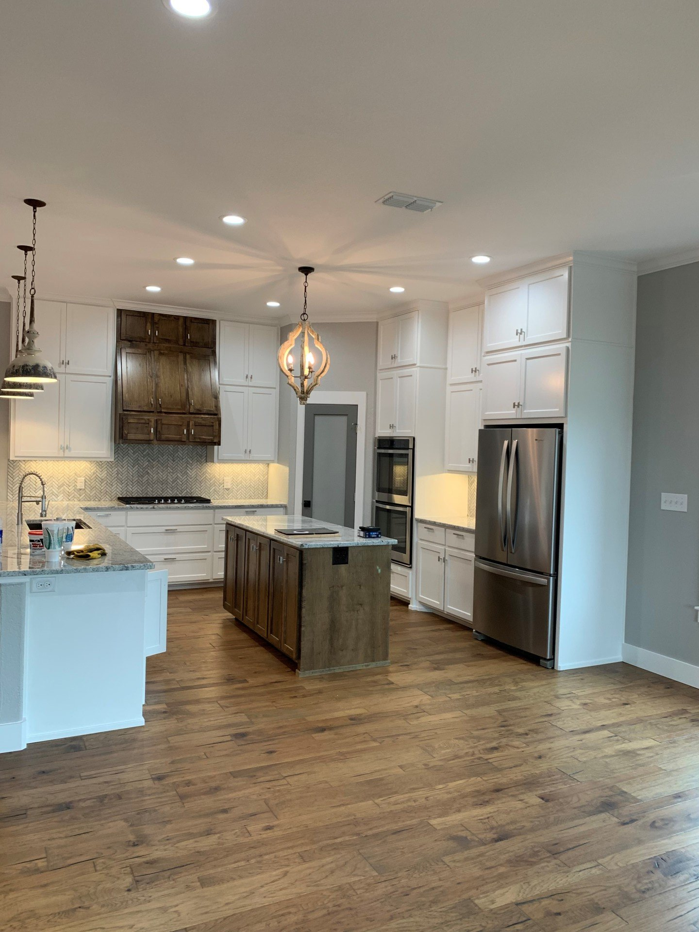 A kitchen with white cabinets , stainless steel appliances , and wooden floors.