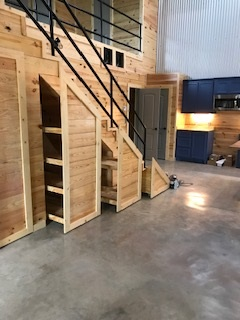 A wooden staircase with shelves underneath it in a room.