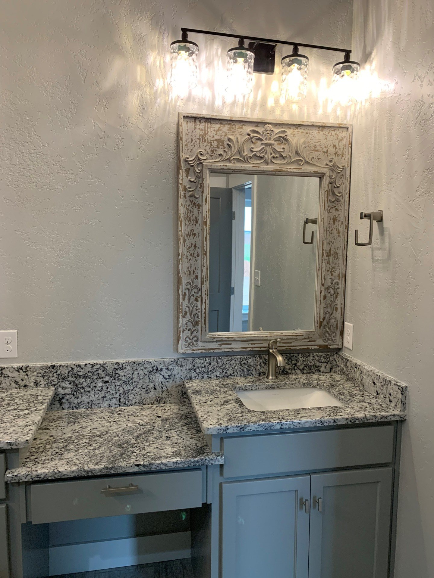 A bathroom with a sink , mirror and light fixture.