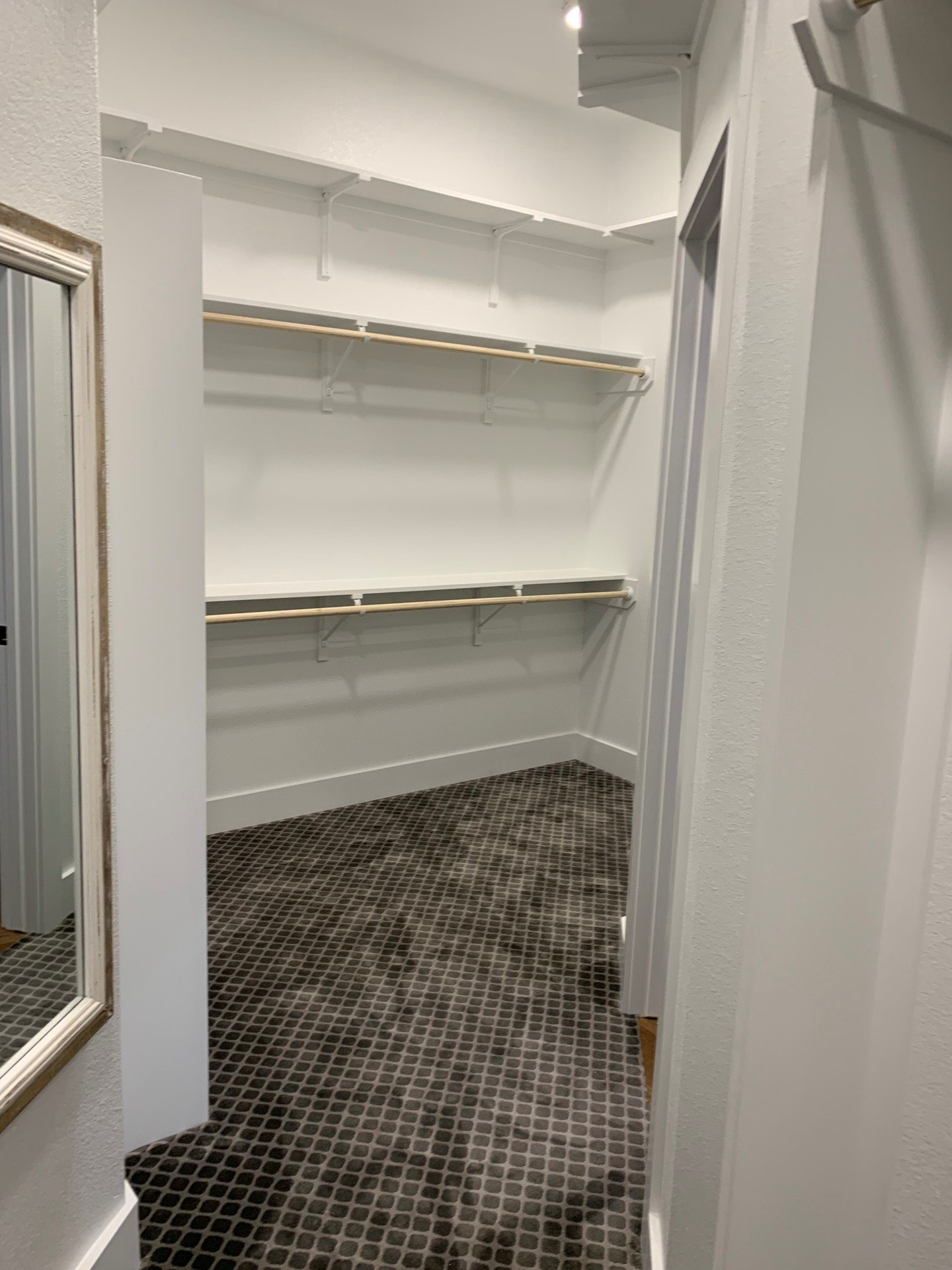 A walk in closet with shelves and a mirror.