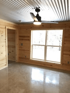 An empty room with a ceiling fan and a window.