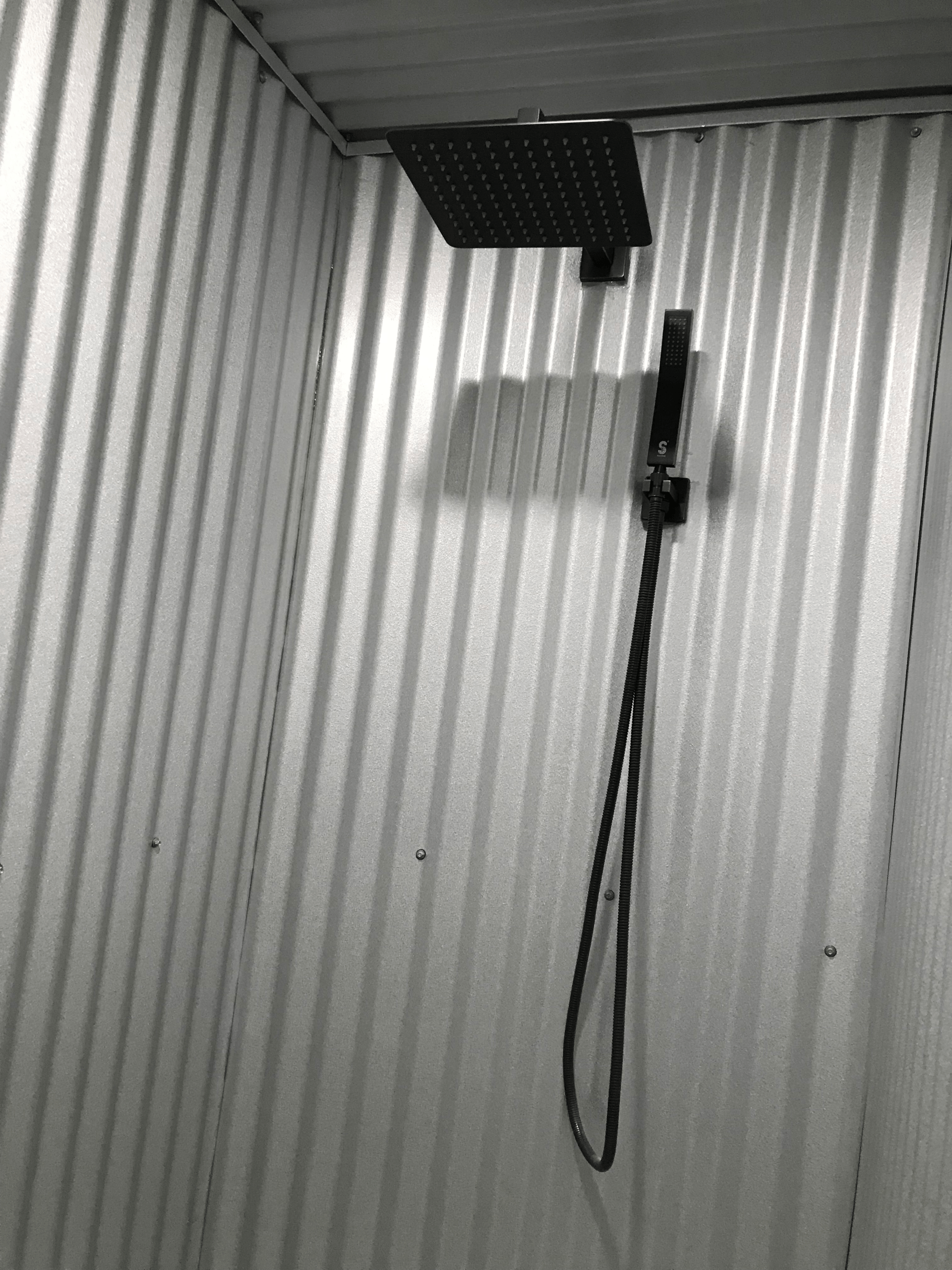A black and white photo of a shower with a shower head hanging from the ceiling.