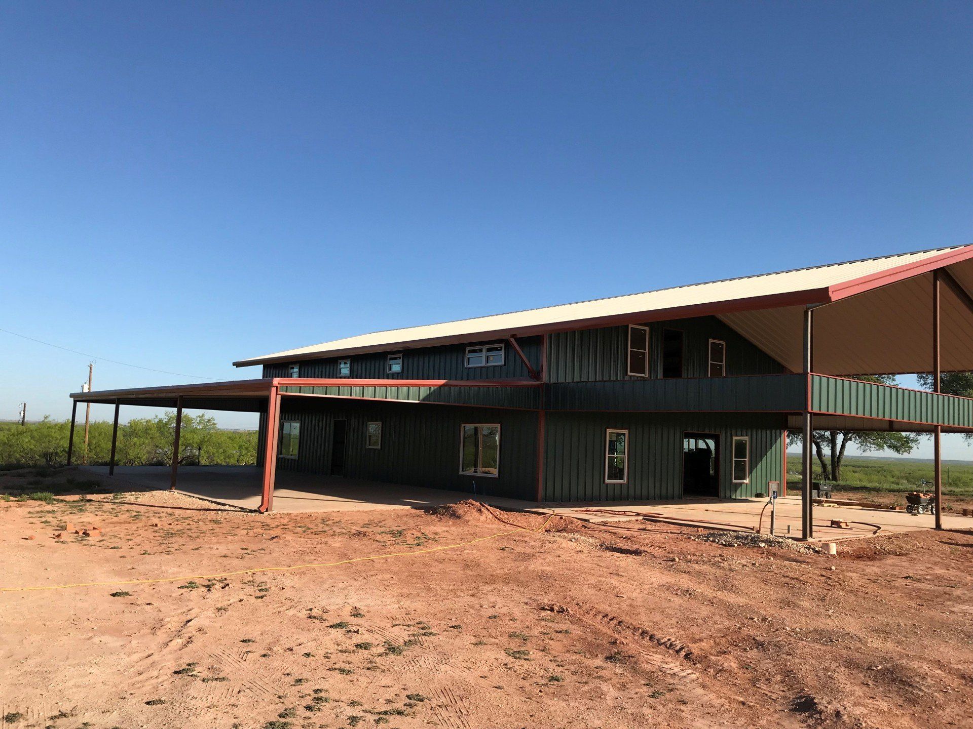 A large house is being built in the middle of a dirt field.
