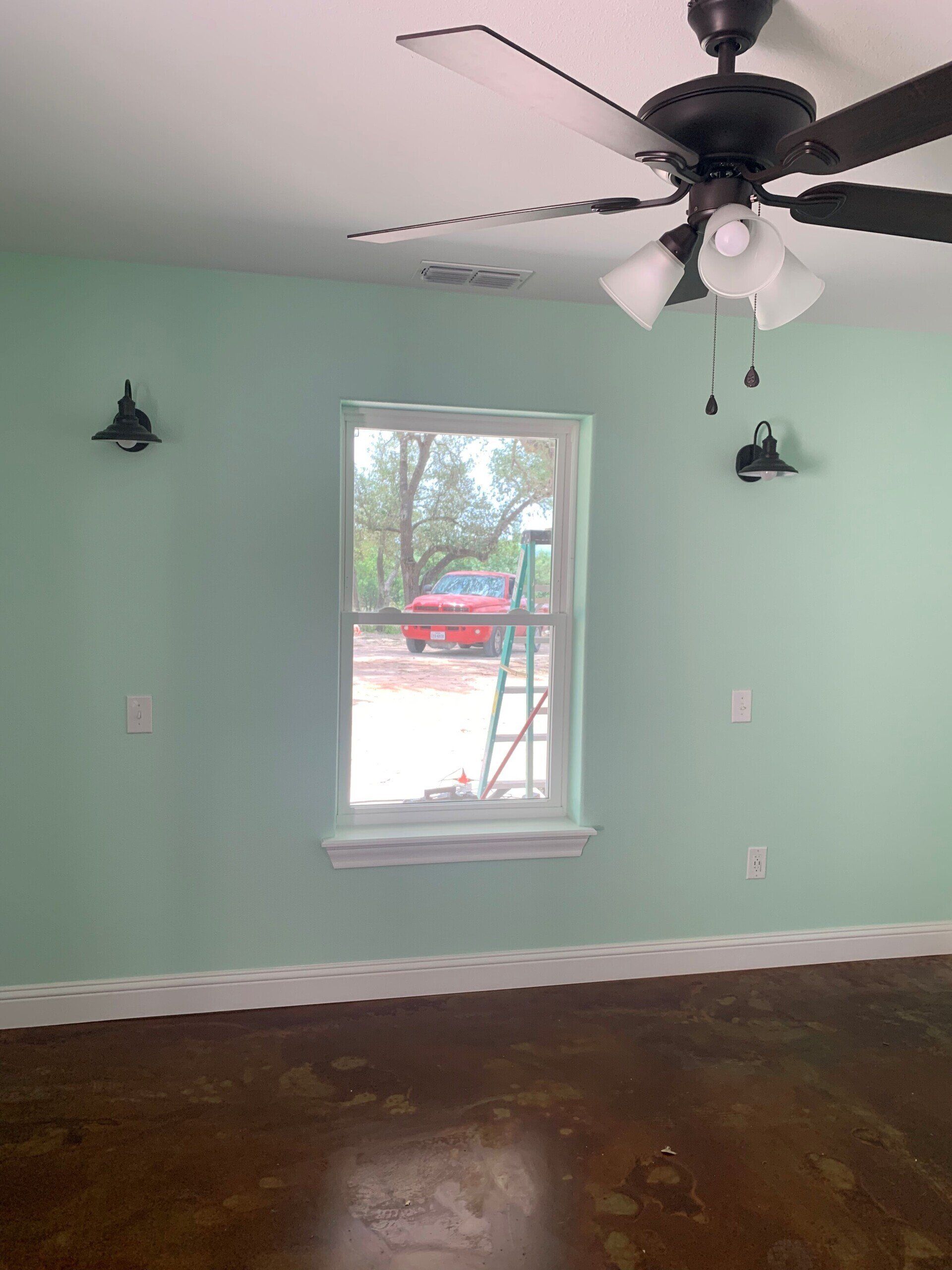 An empty room with a ceiling fan and a window