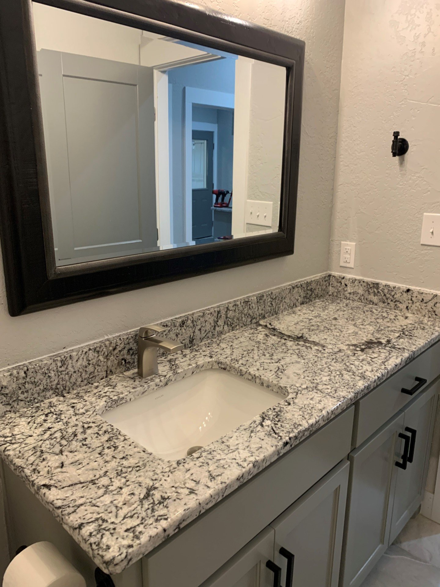 A bathroom with a sink , mirror and granite counter top.