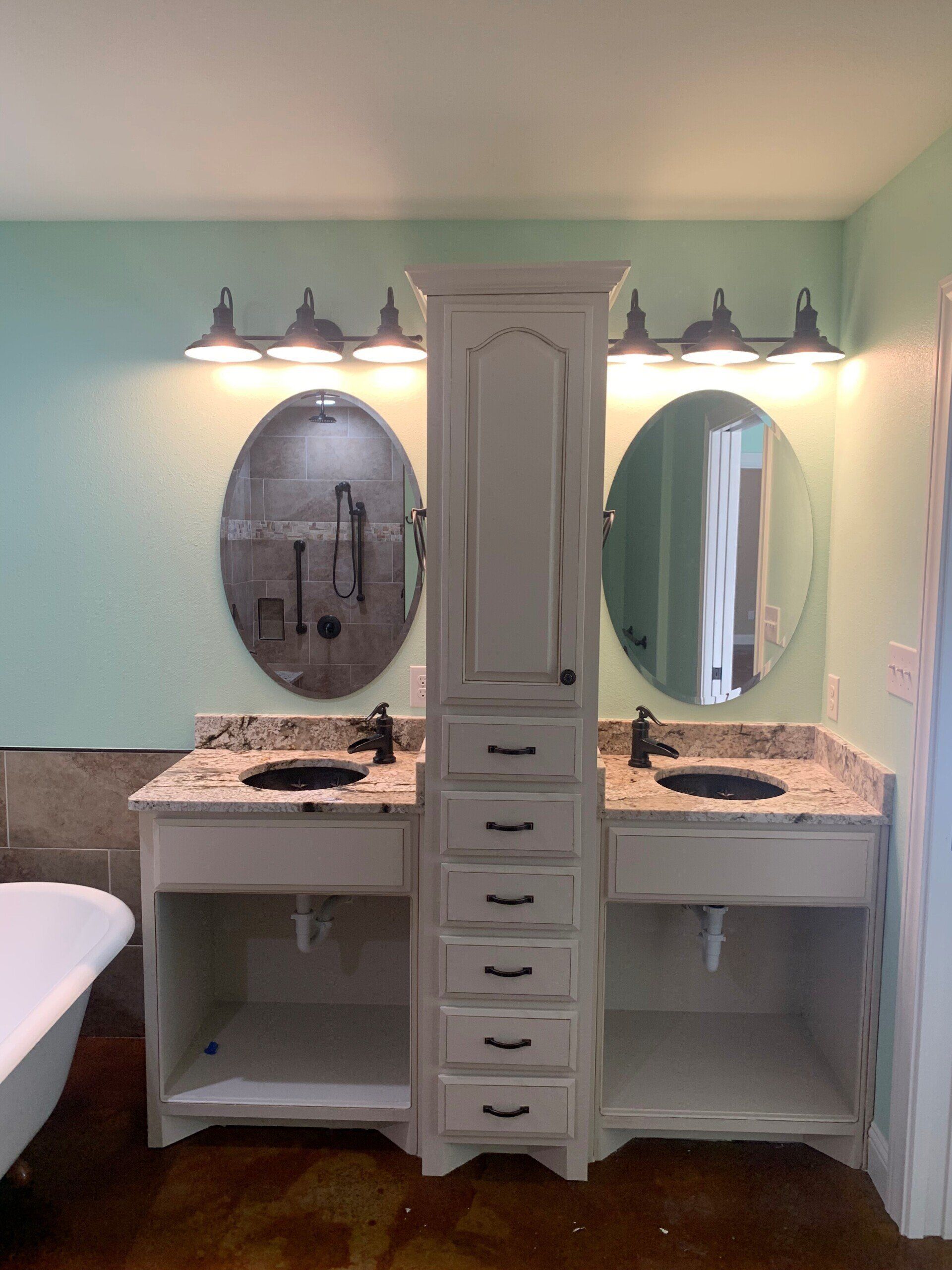 A bathroom with two sinks , two mirrors and a bathtub.
