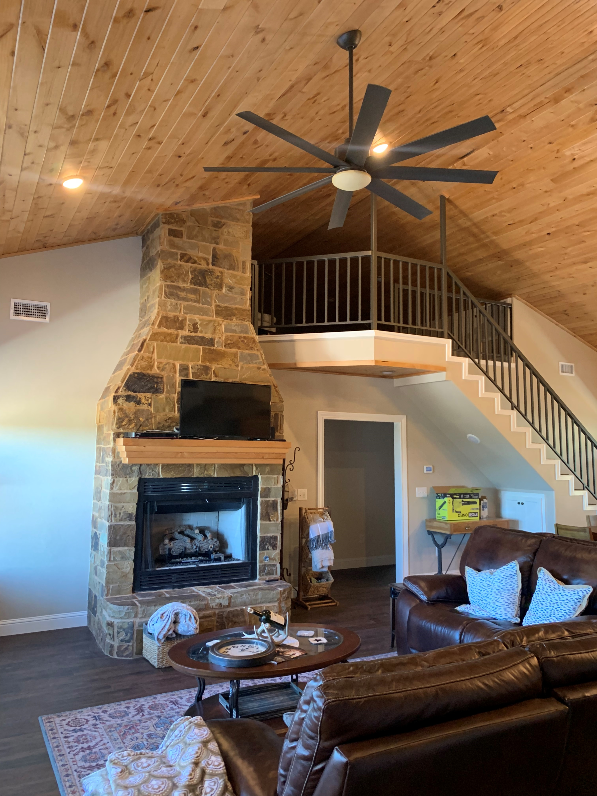 A living room with a fireplace and a ceiling fan