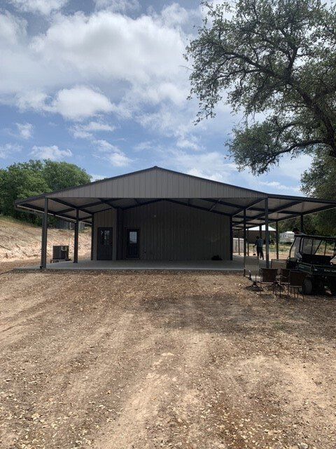 A large metal building with a covered porch and a vehicle parked in front of it.