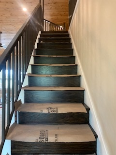 A set of wooden stairs with a metal railing in a house.