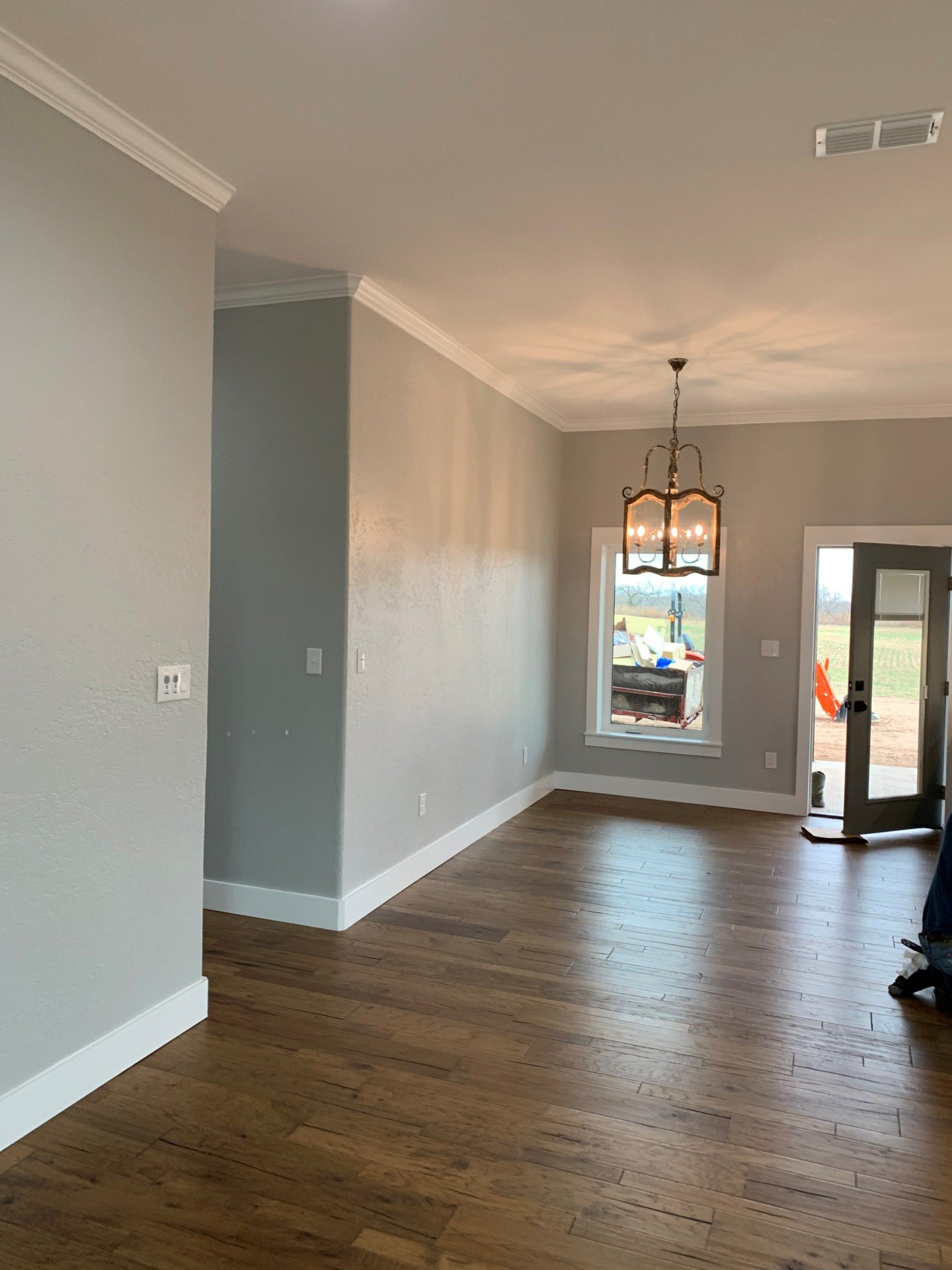 An empty living room with hardwood floors and gray walls.