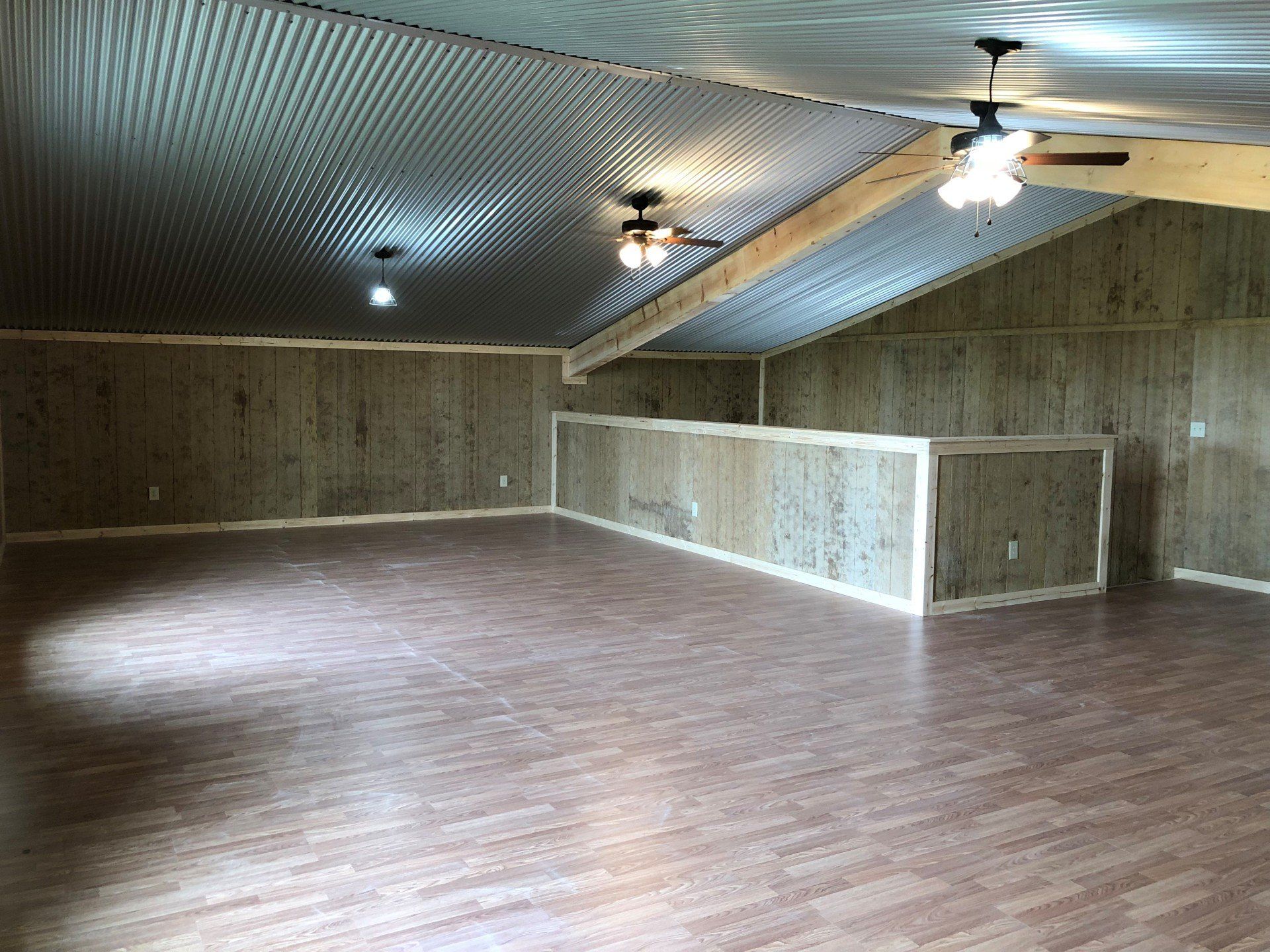 A large empty room with a wooden floor and ceiling fan.