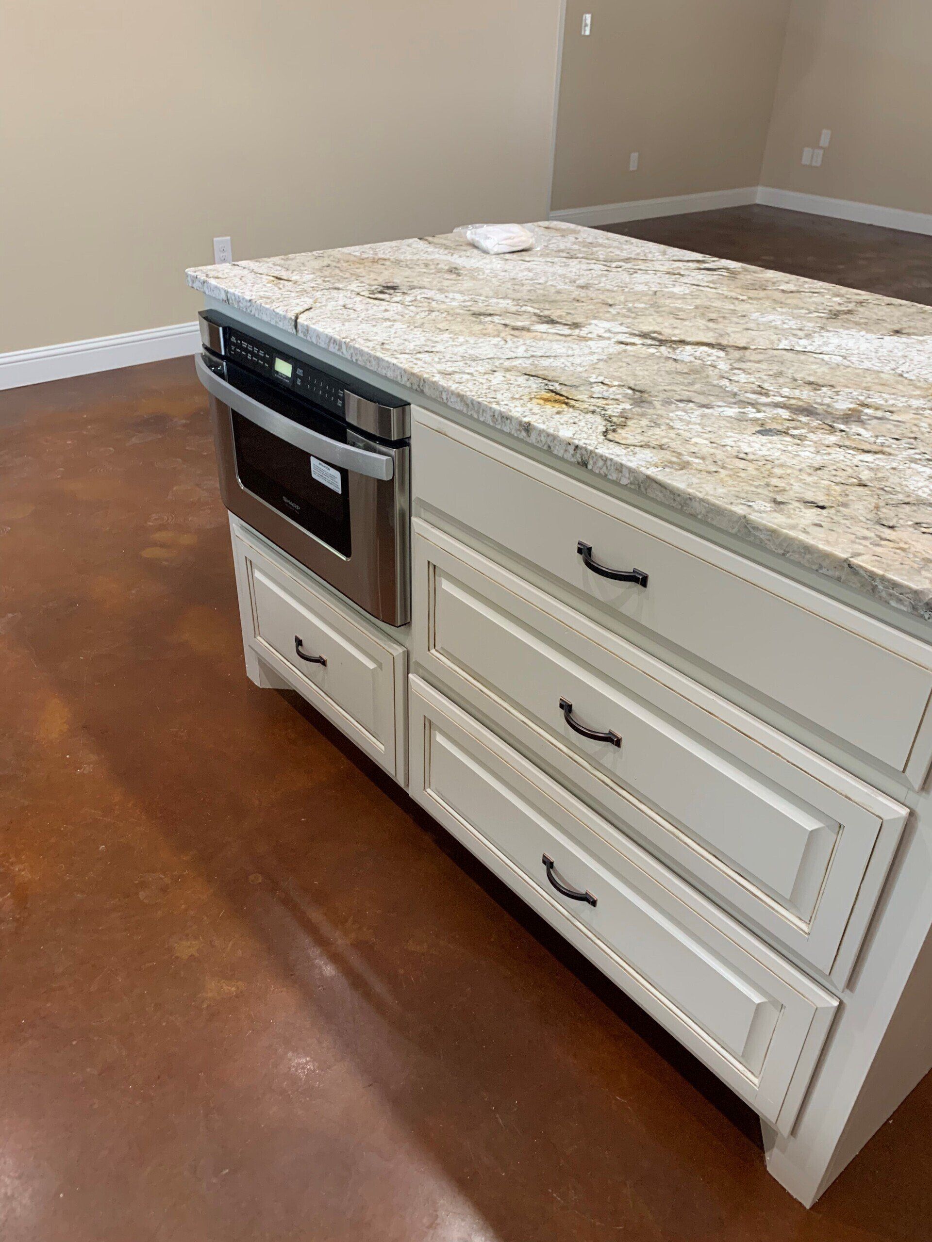 A kitchen island with stainless steel appliances and granite counter tops.