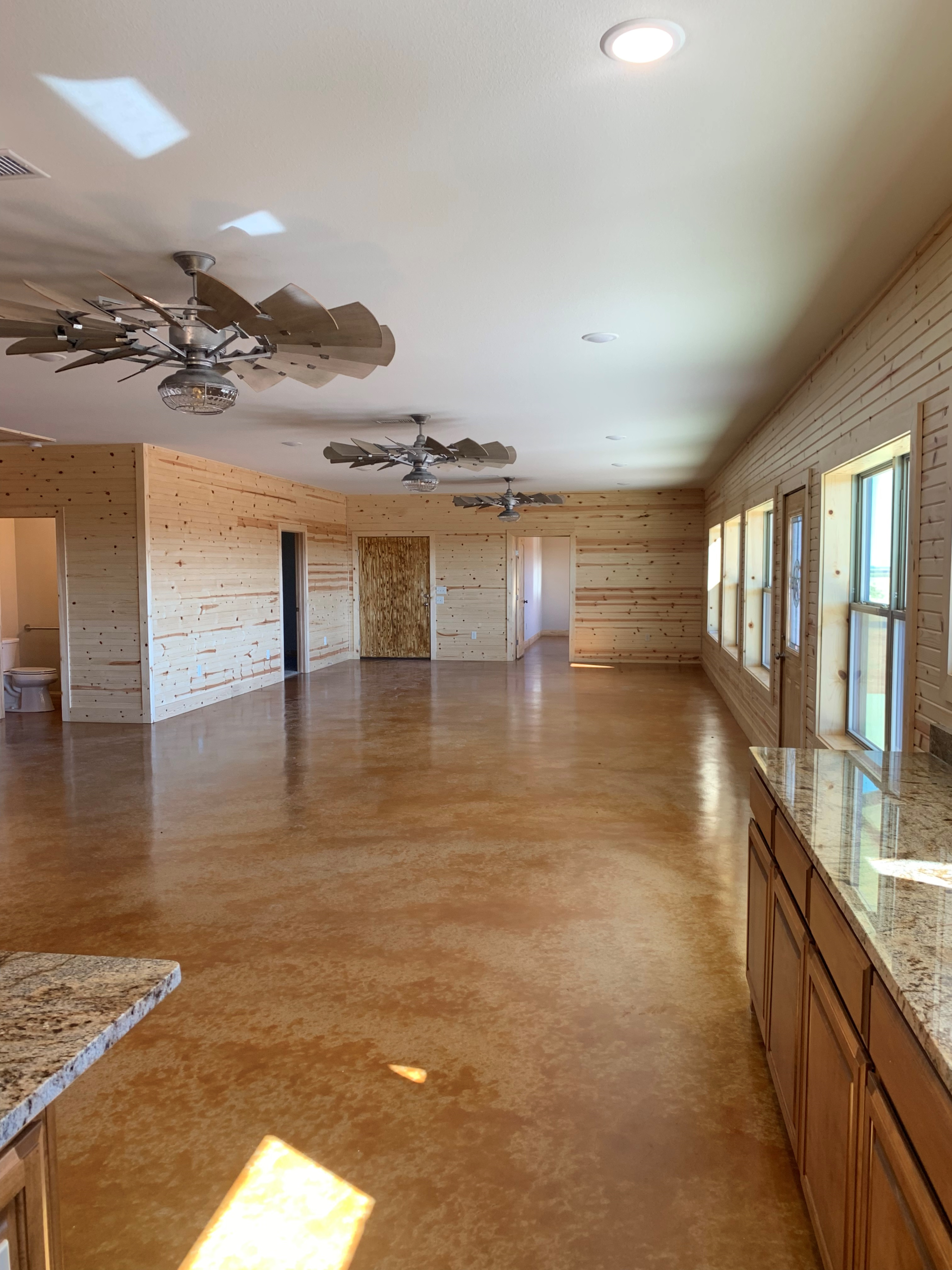 An empty room with a ceiling fan and a lot of windows