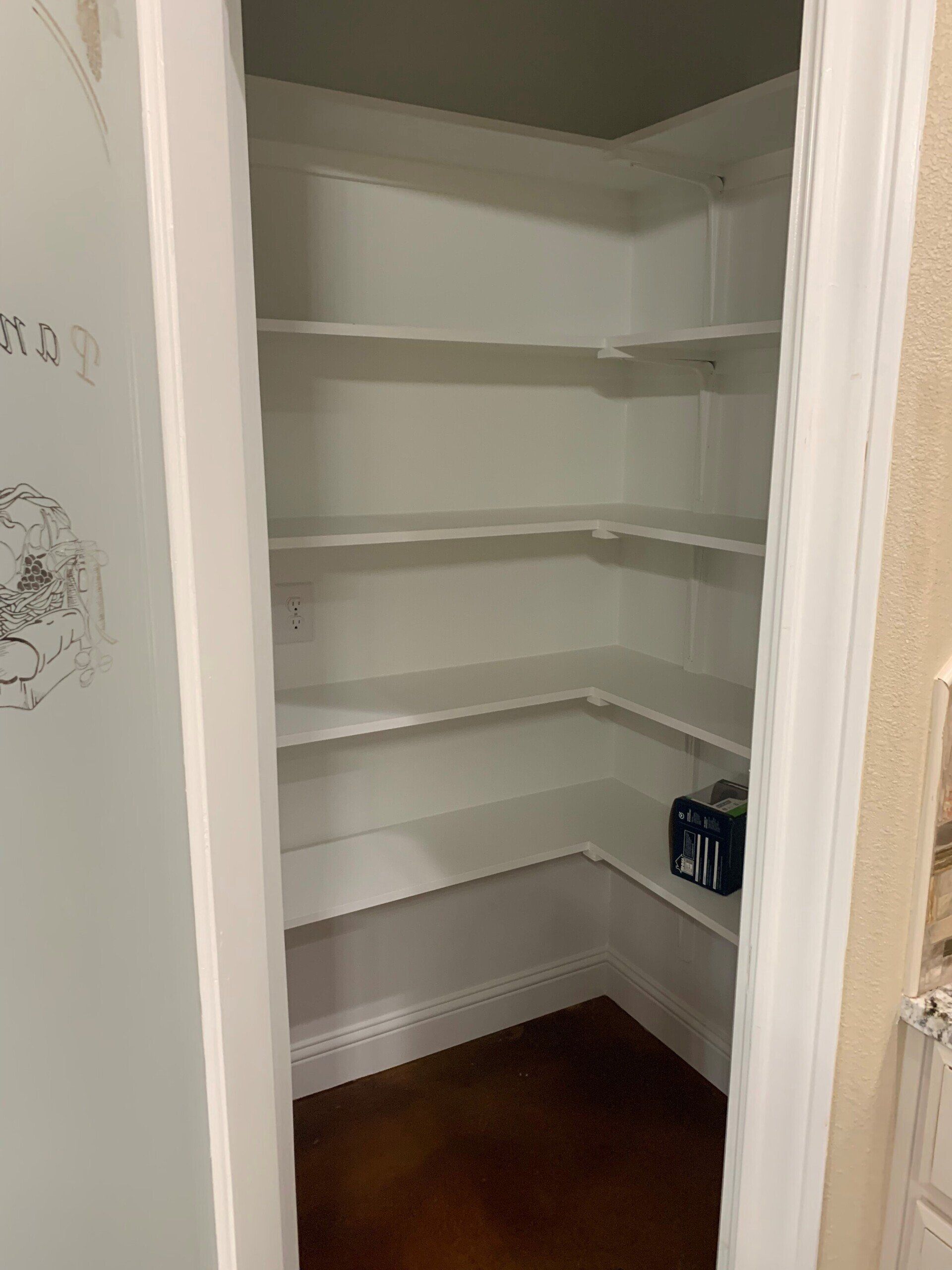 A pantry with white shelves and a wooden floor in a house.