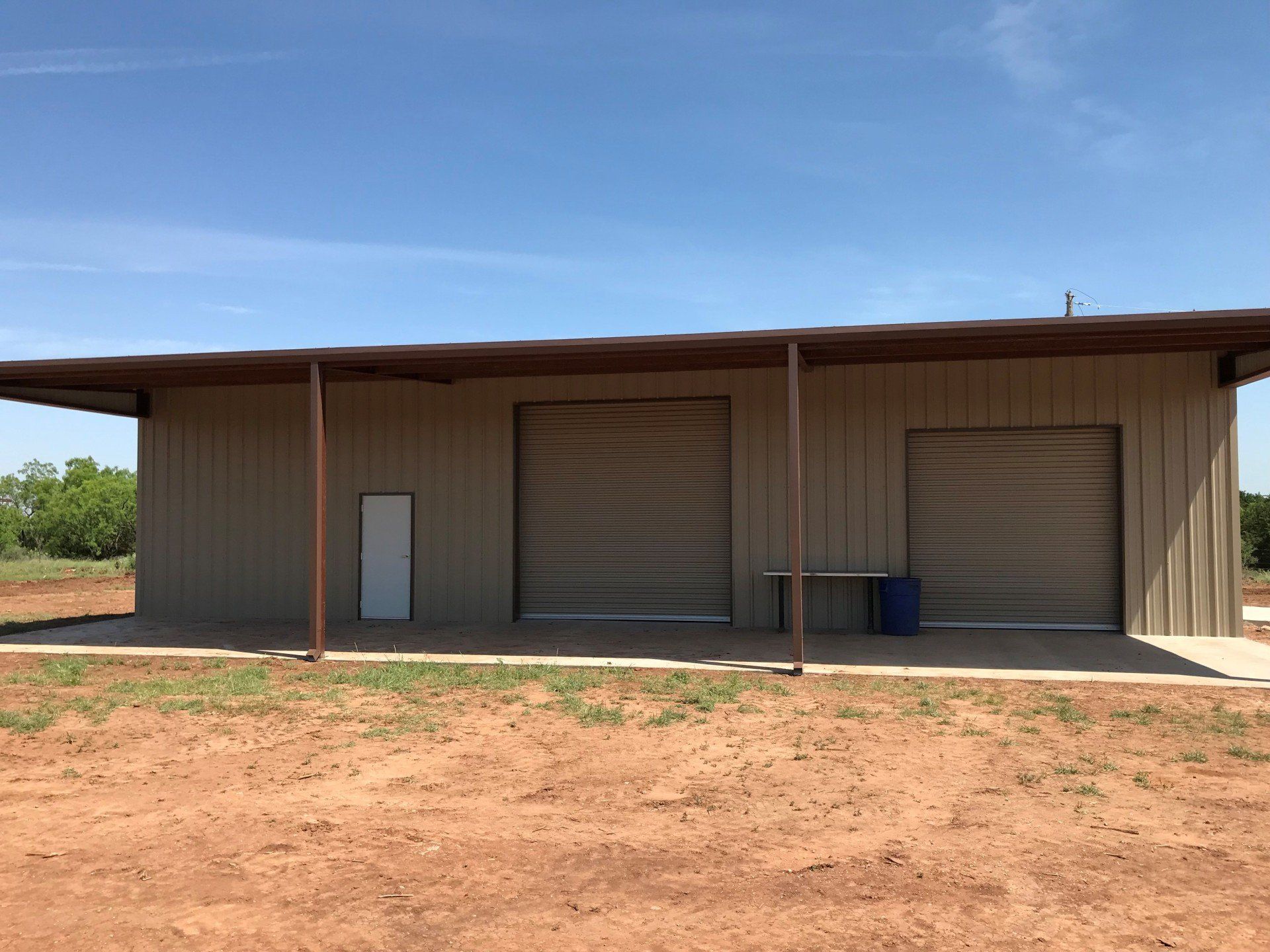 A large metal building with two garage doors and a porch.