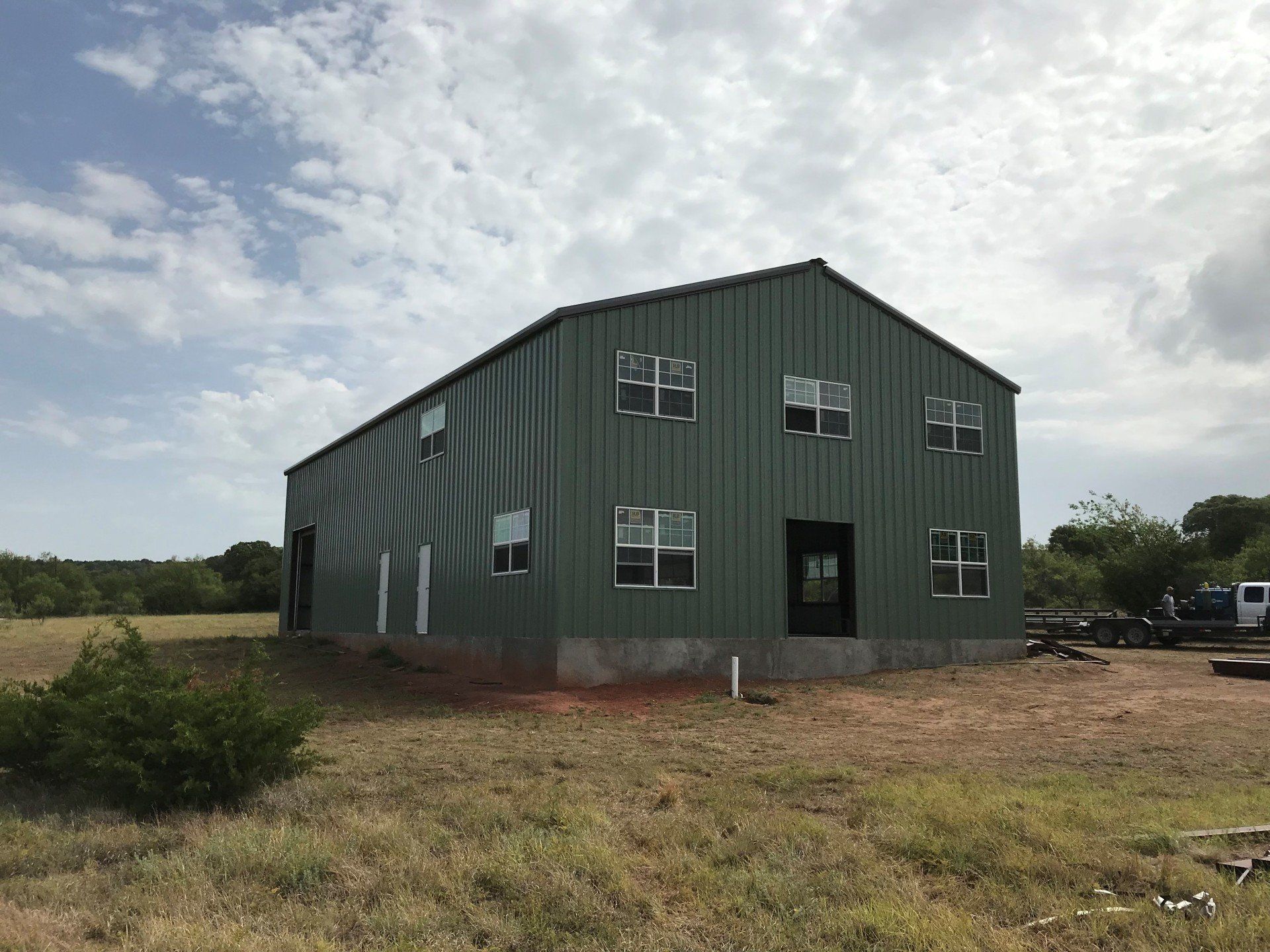 A green building with a lot of windows is sitting in the middle of a field.