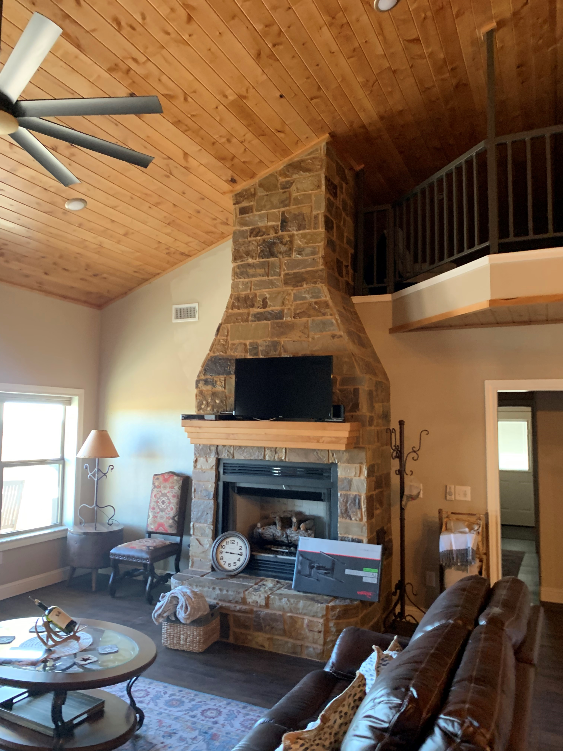A living room with a fireplace and a ceiling fan