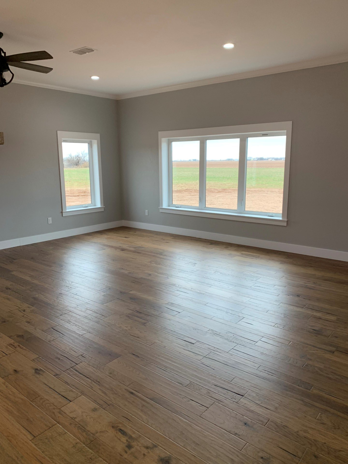 An empty living room with hardwood floors and a ceiling fan.