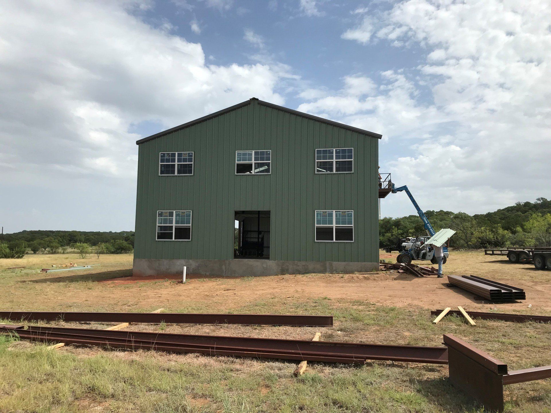A large green building is being built in a field.