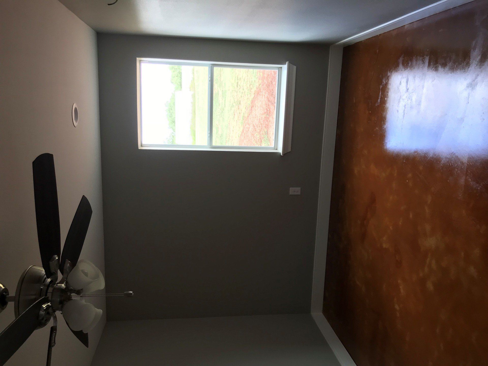 A room with a ceiling fan and a window.