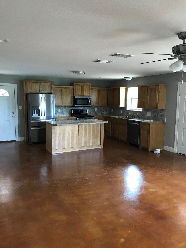 An empty kitchen with stainless steel appliances and wooden cabinets.