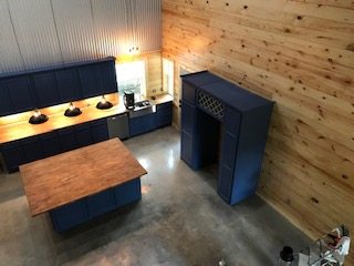 An aerial view of a kitchen with blue cabinets and wooden walls.