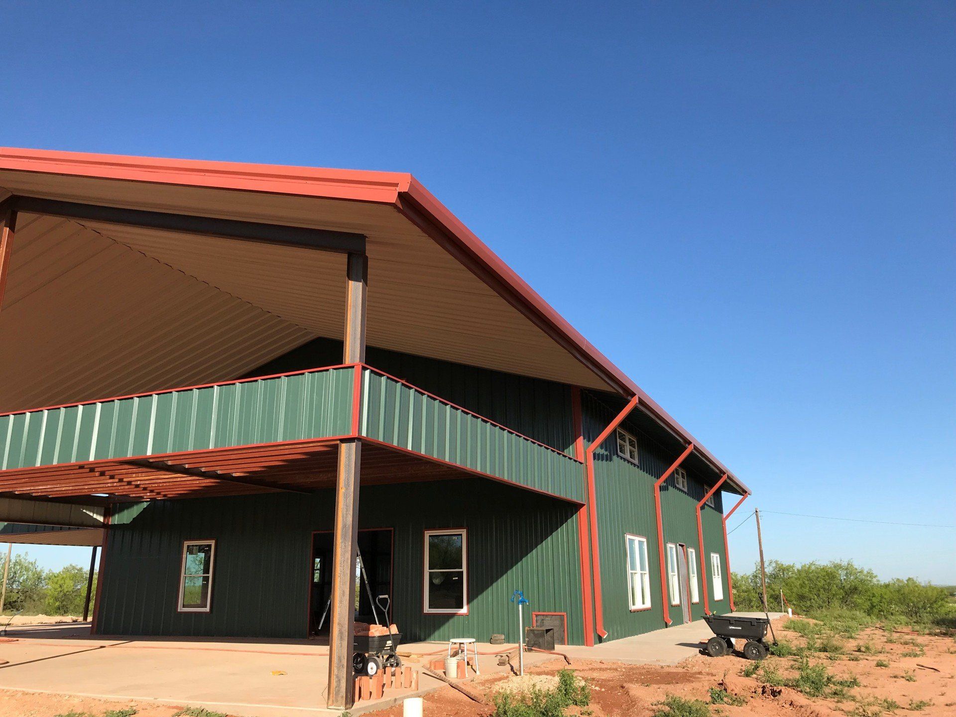 A large green building with a red roof is under construction.