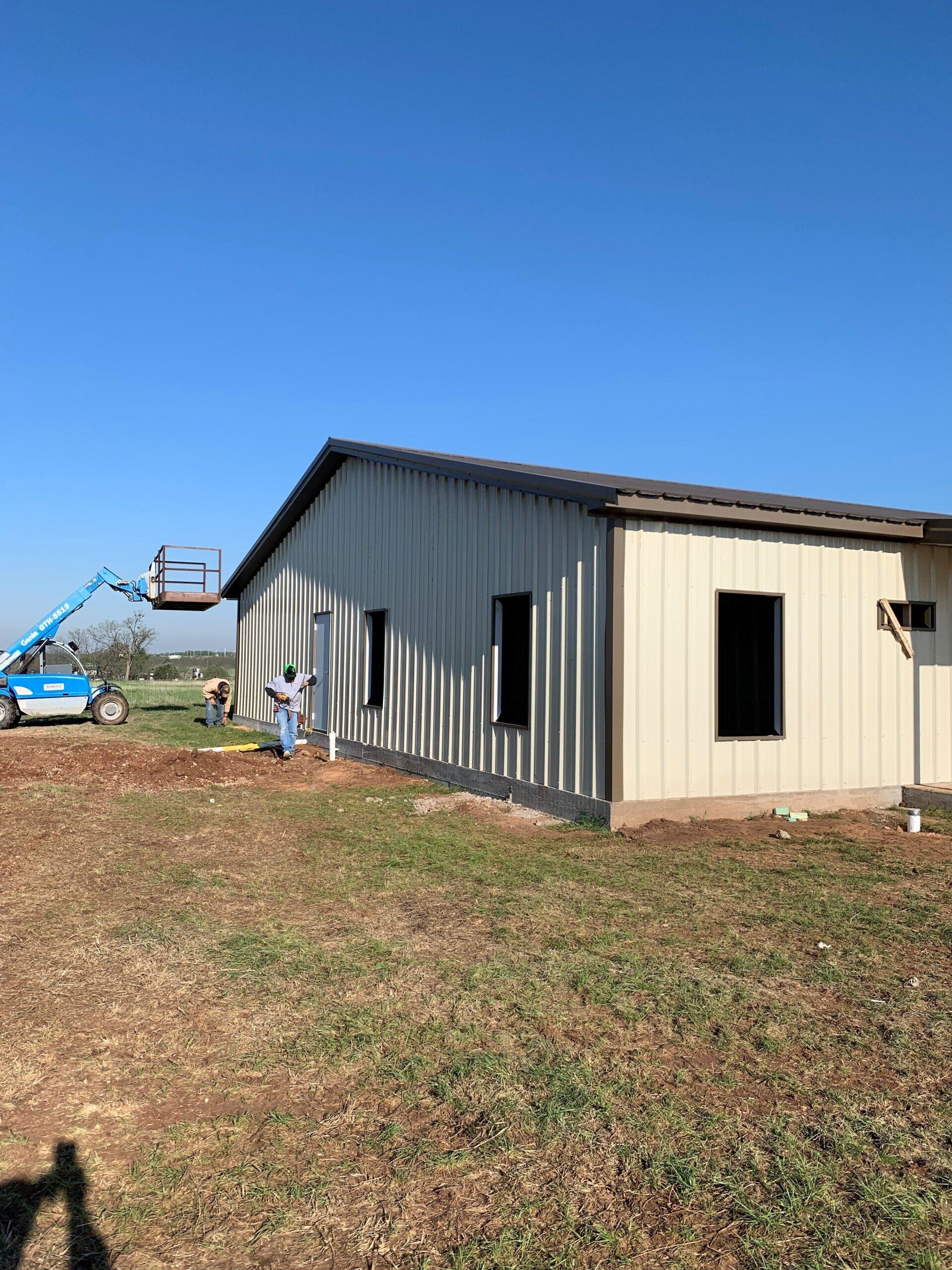 A large metal building is being built in a field.