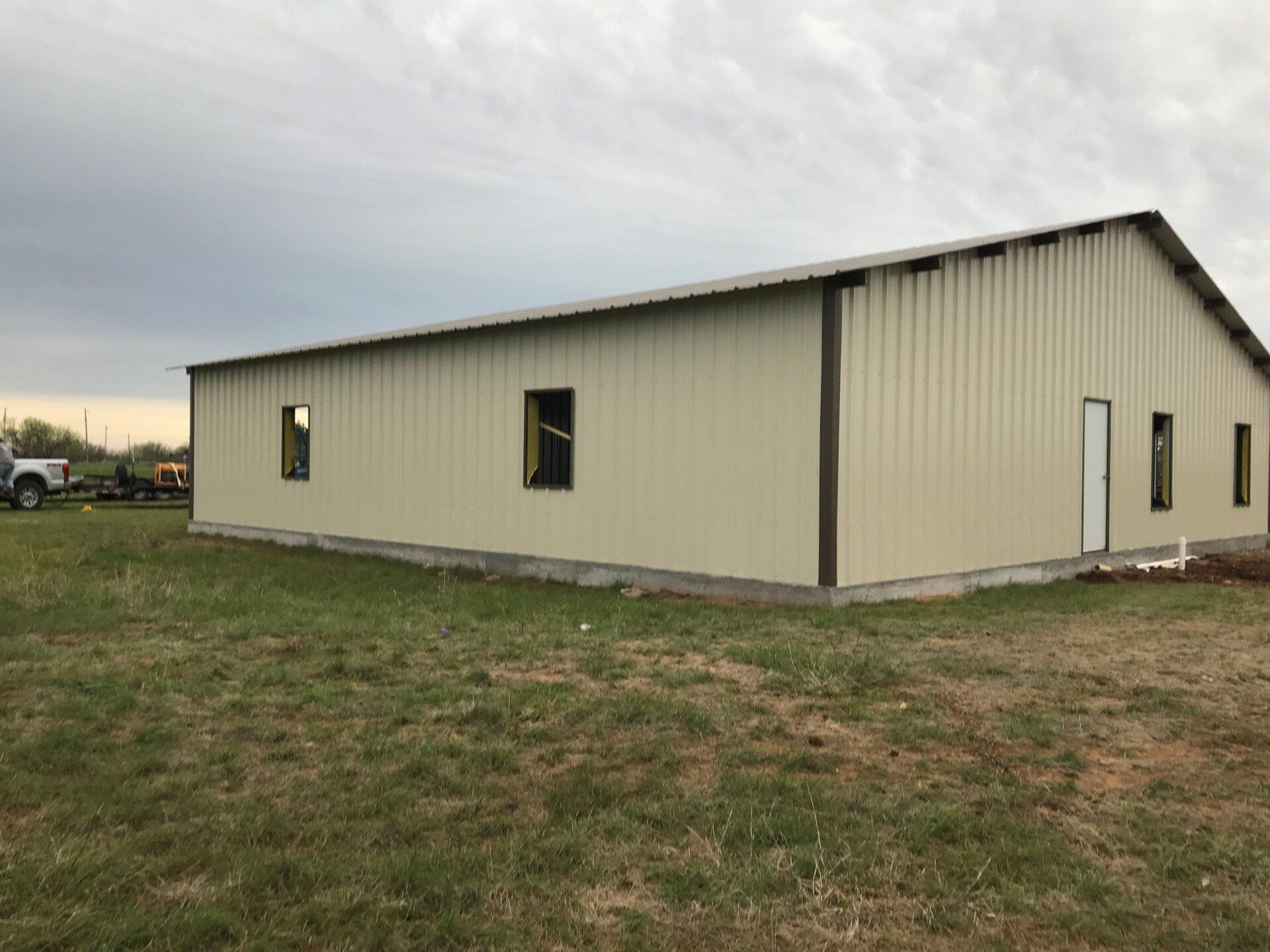 A large metal building is sitting in the middle of a grassy field.