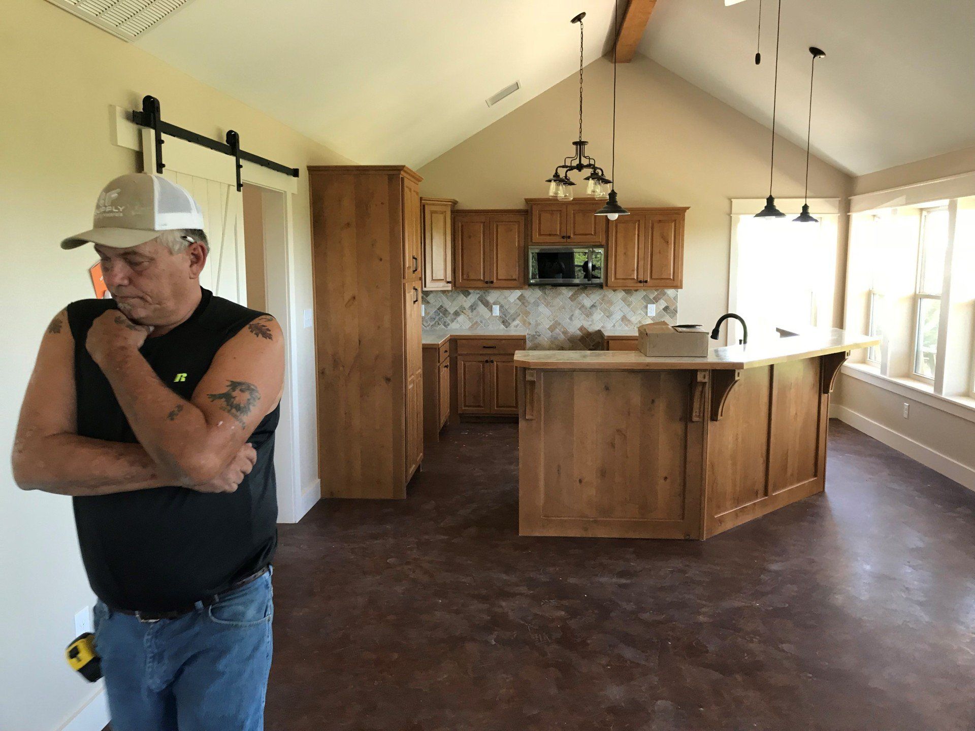 A man is standing in a kitchen with his arms crossed