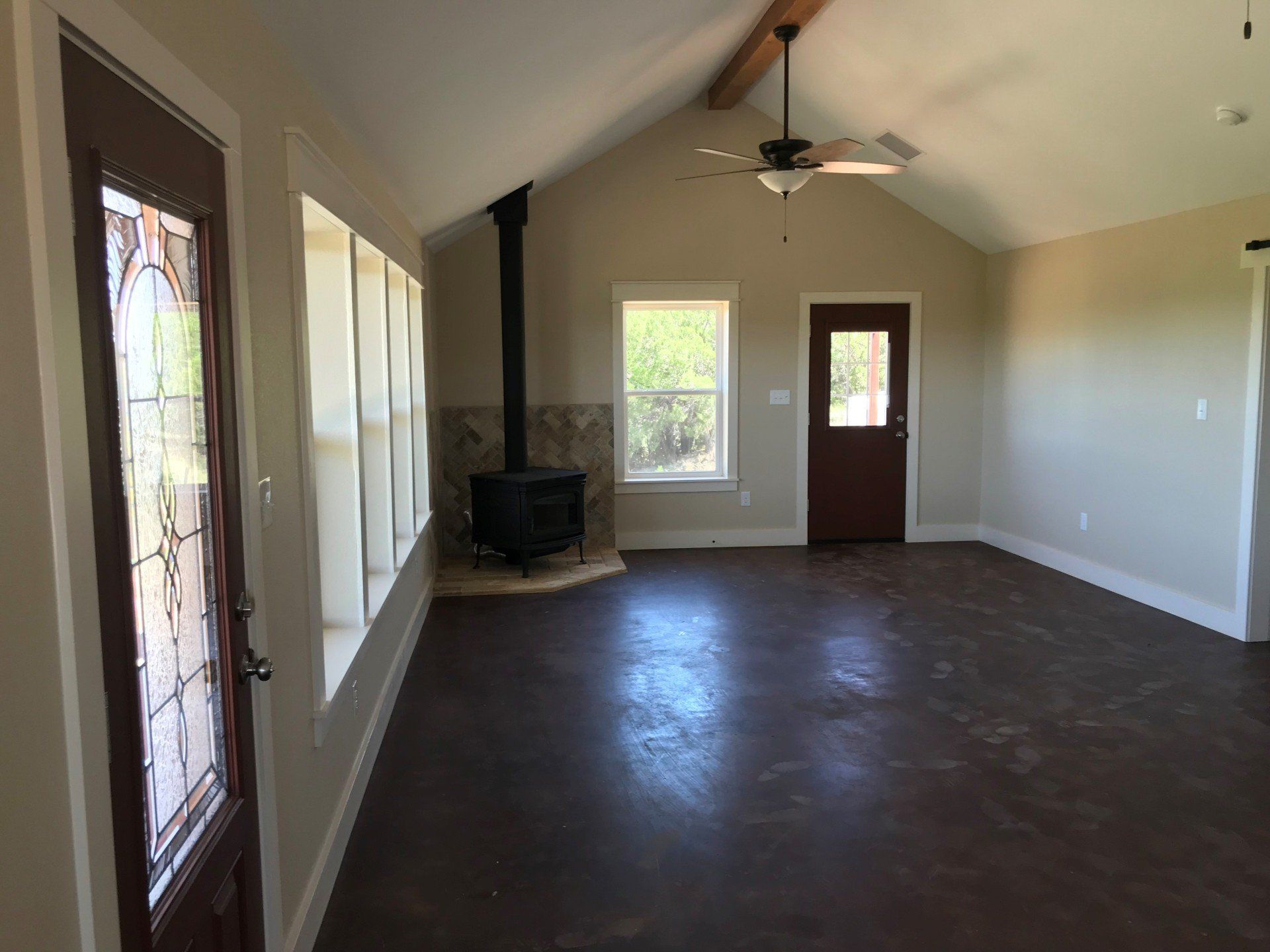 An empty living room with a fireplace and a ceiling fan