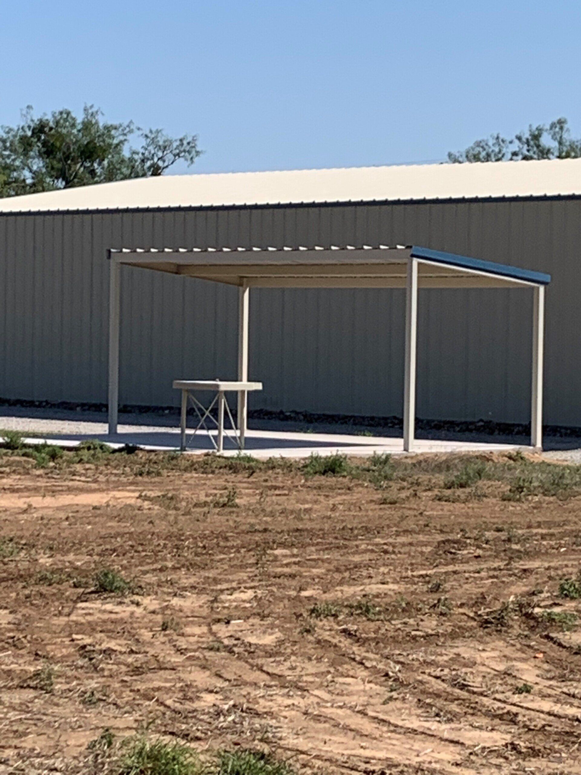 A covered area with a picnic table in front of a building