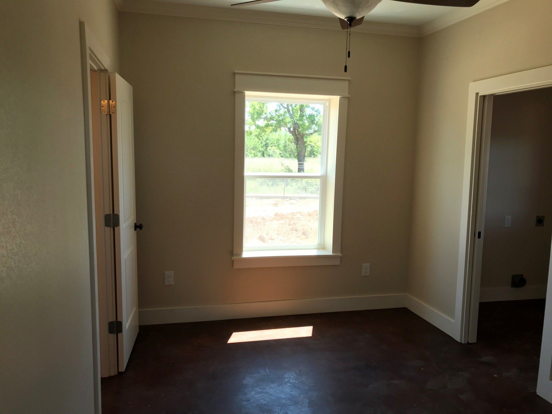 An empty room with a window and a ceiling fan