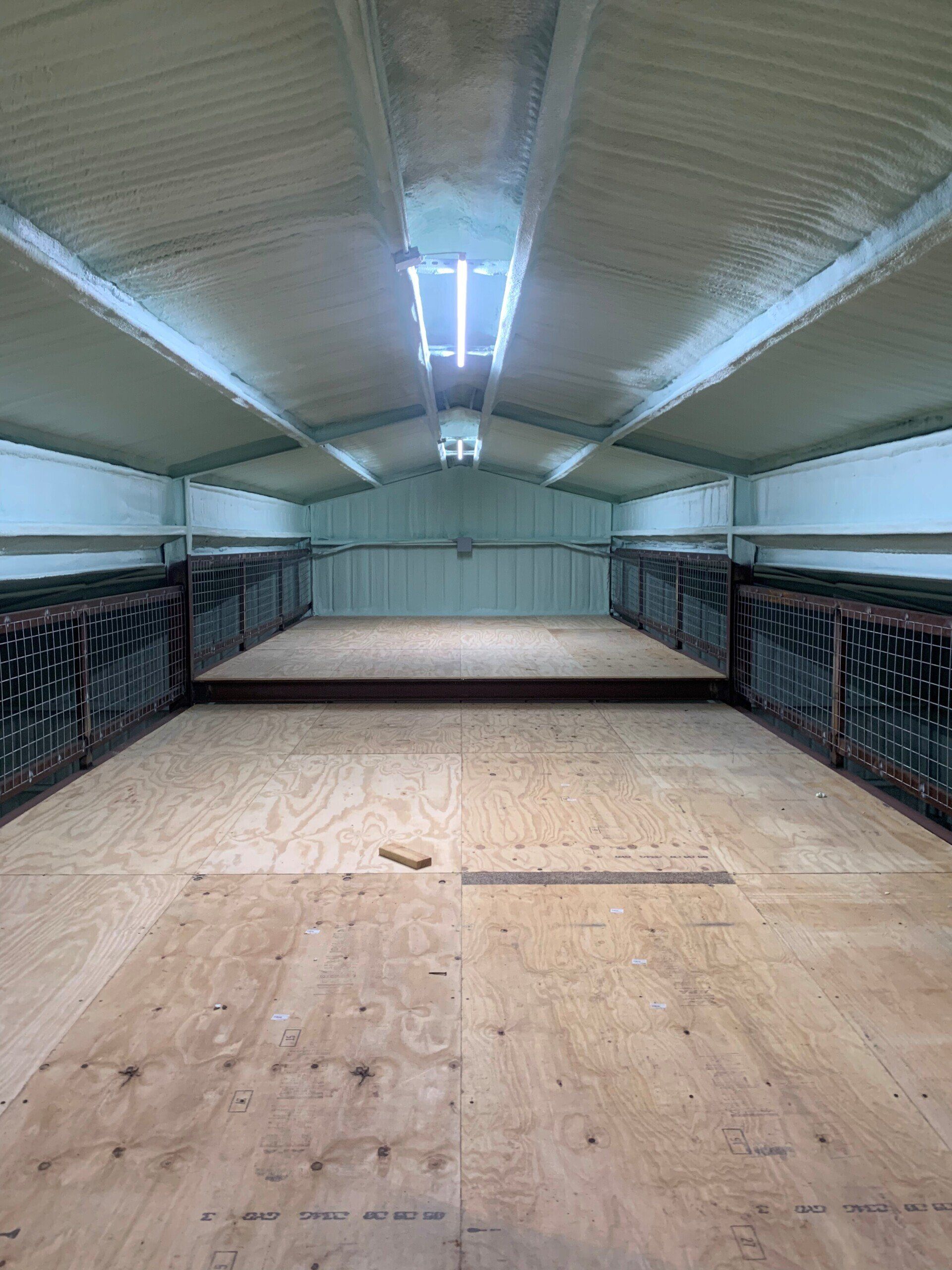 A large empty room with a wooden floor and a ceiling.