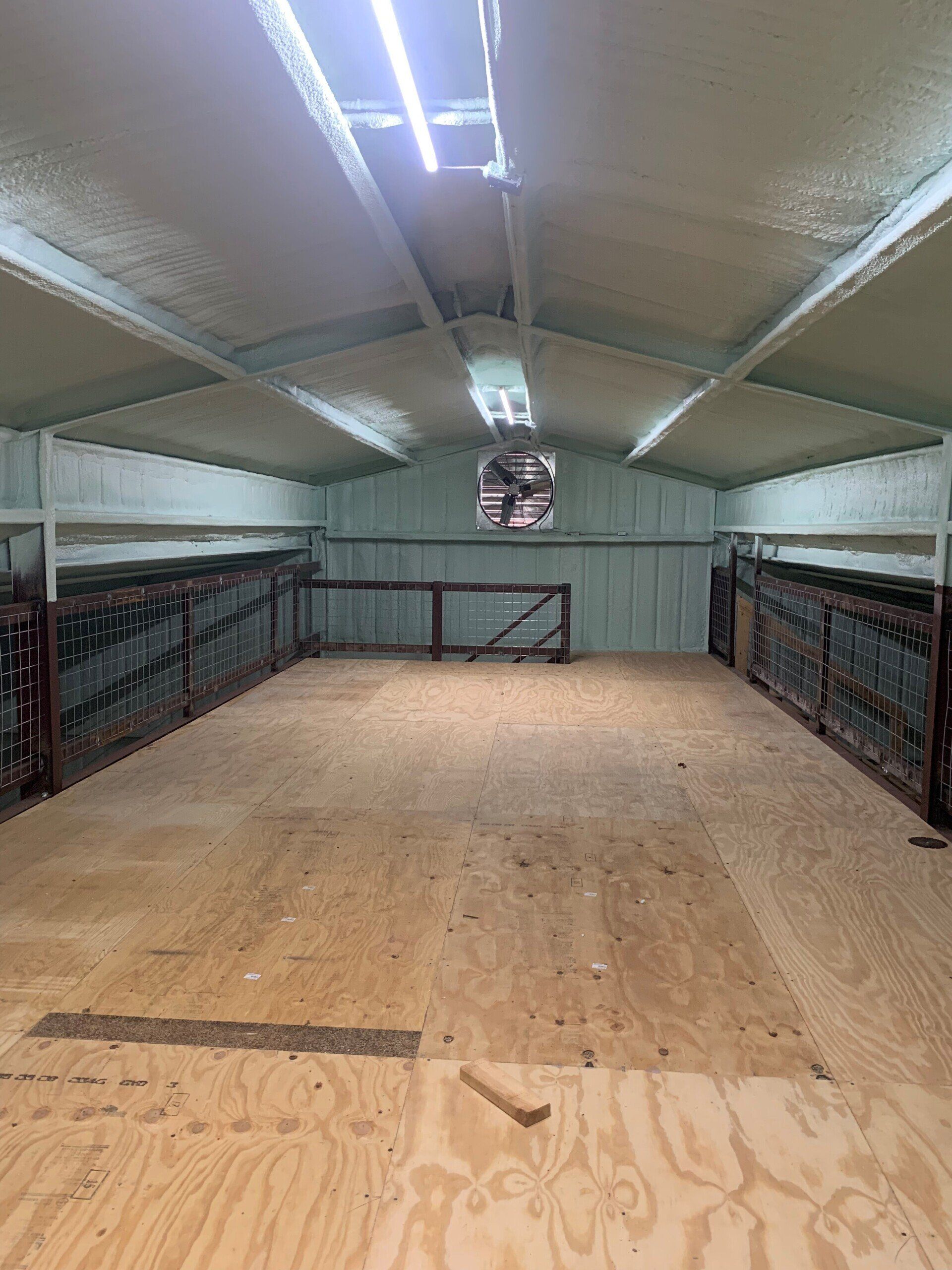 An empty barn with a wooden floor and a fence.