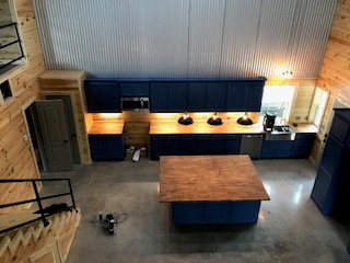 An aerial view of a kitchen with blue cabinets and a wooden island