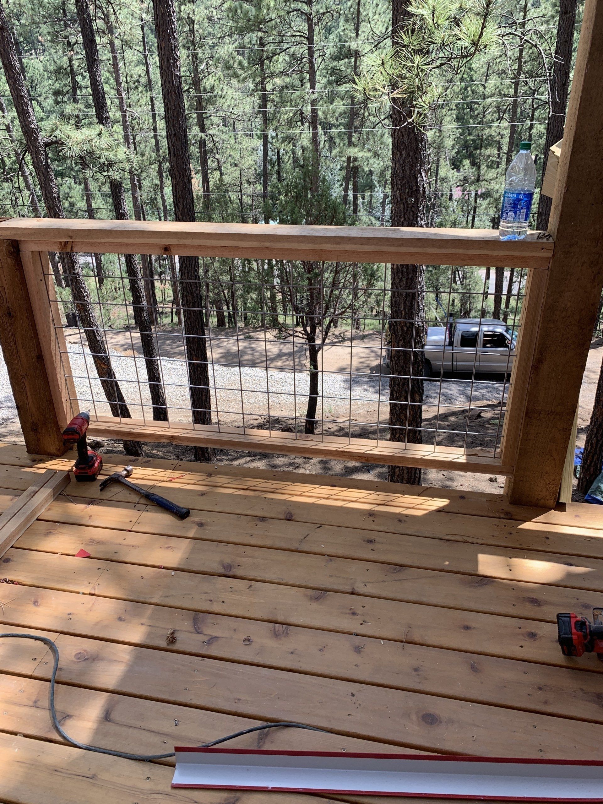 A wooden deck with a railing being built in the woods.