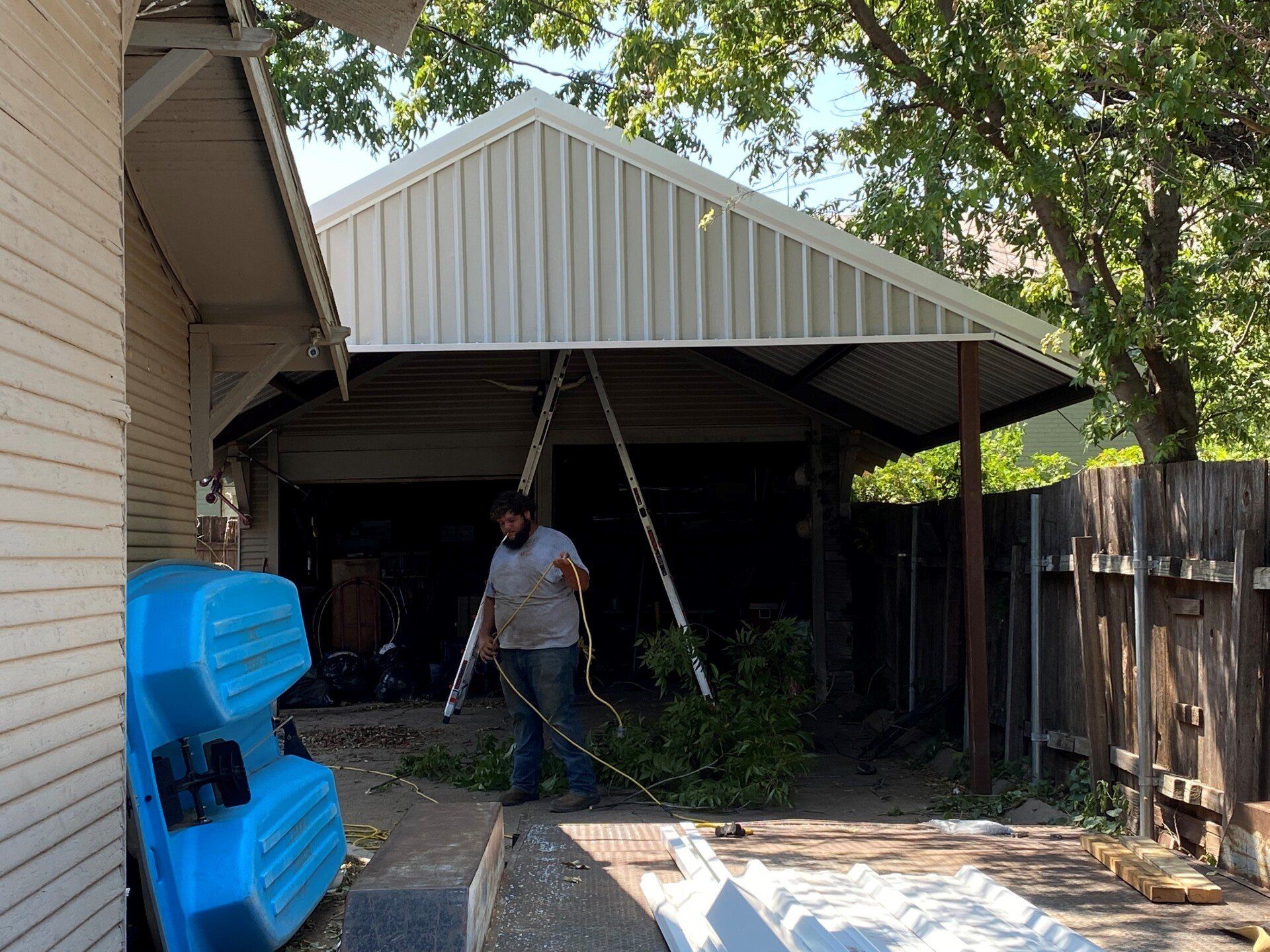 A man is working on a carport in front of a house.
