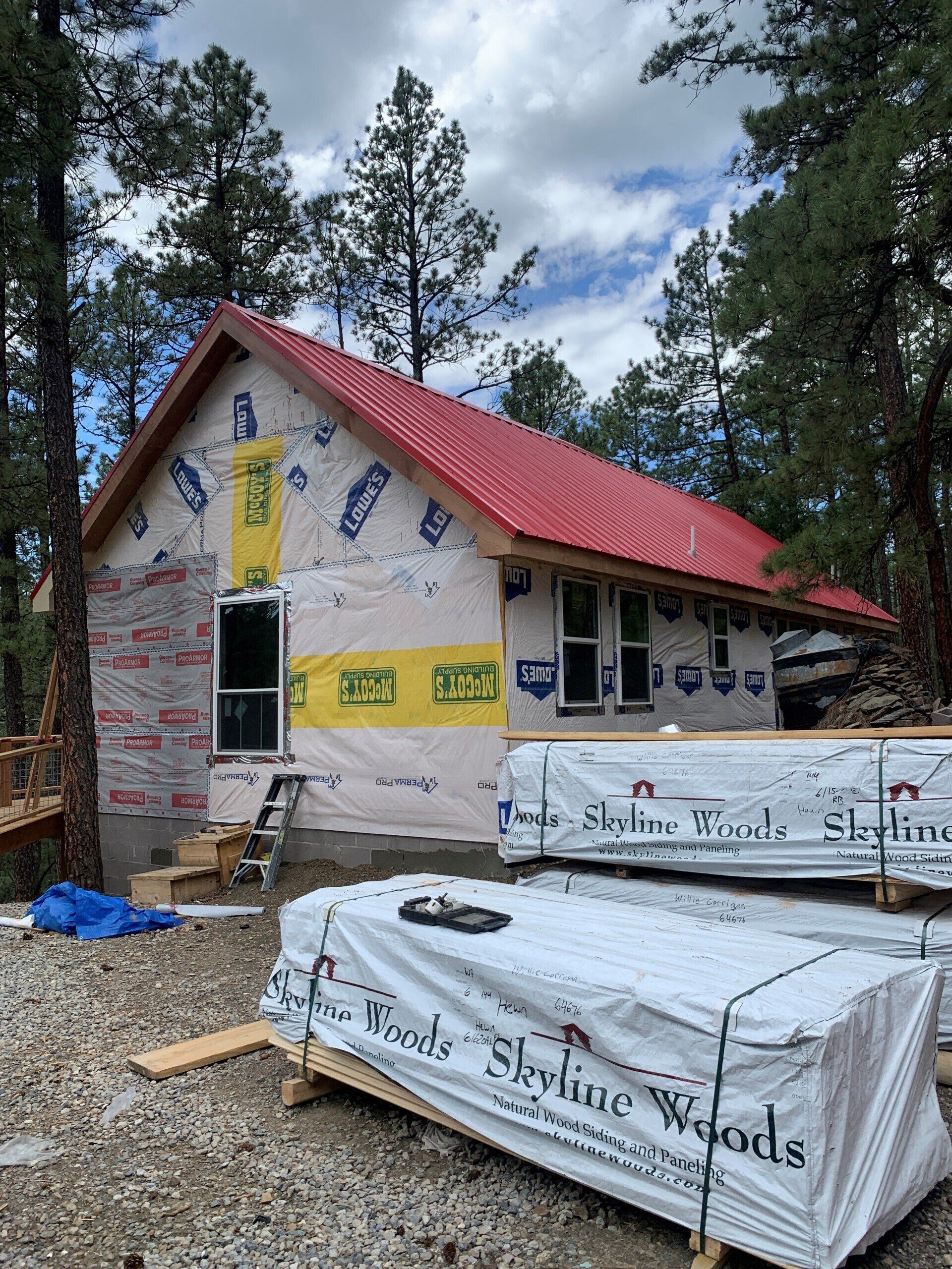 A small house with a red roof is being built in the woods.