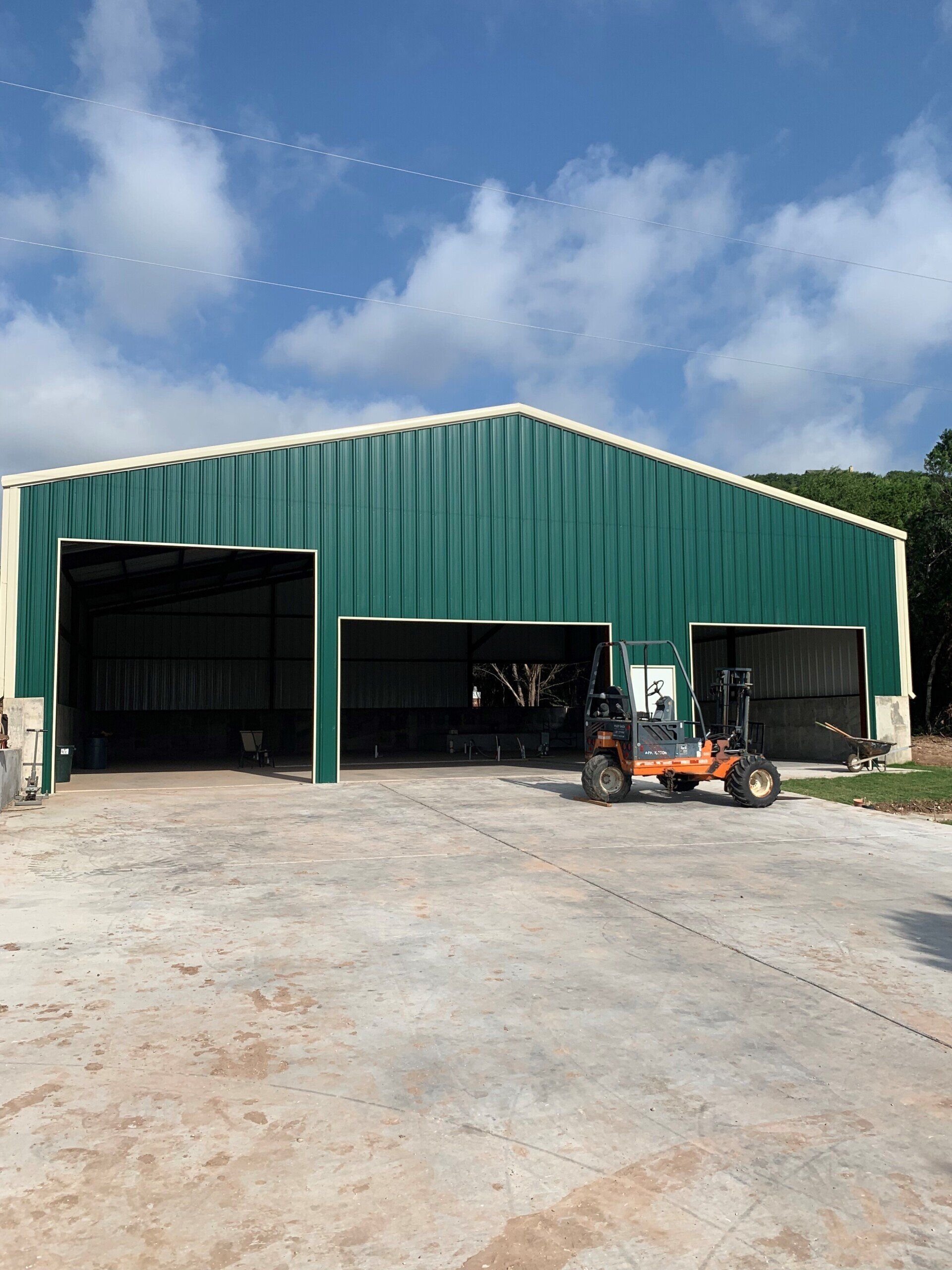 A green building with a forklift parked in front of it