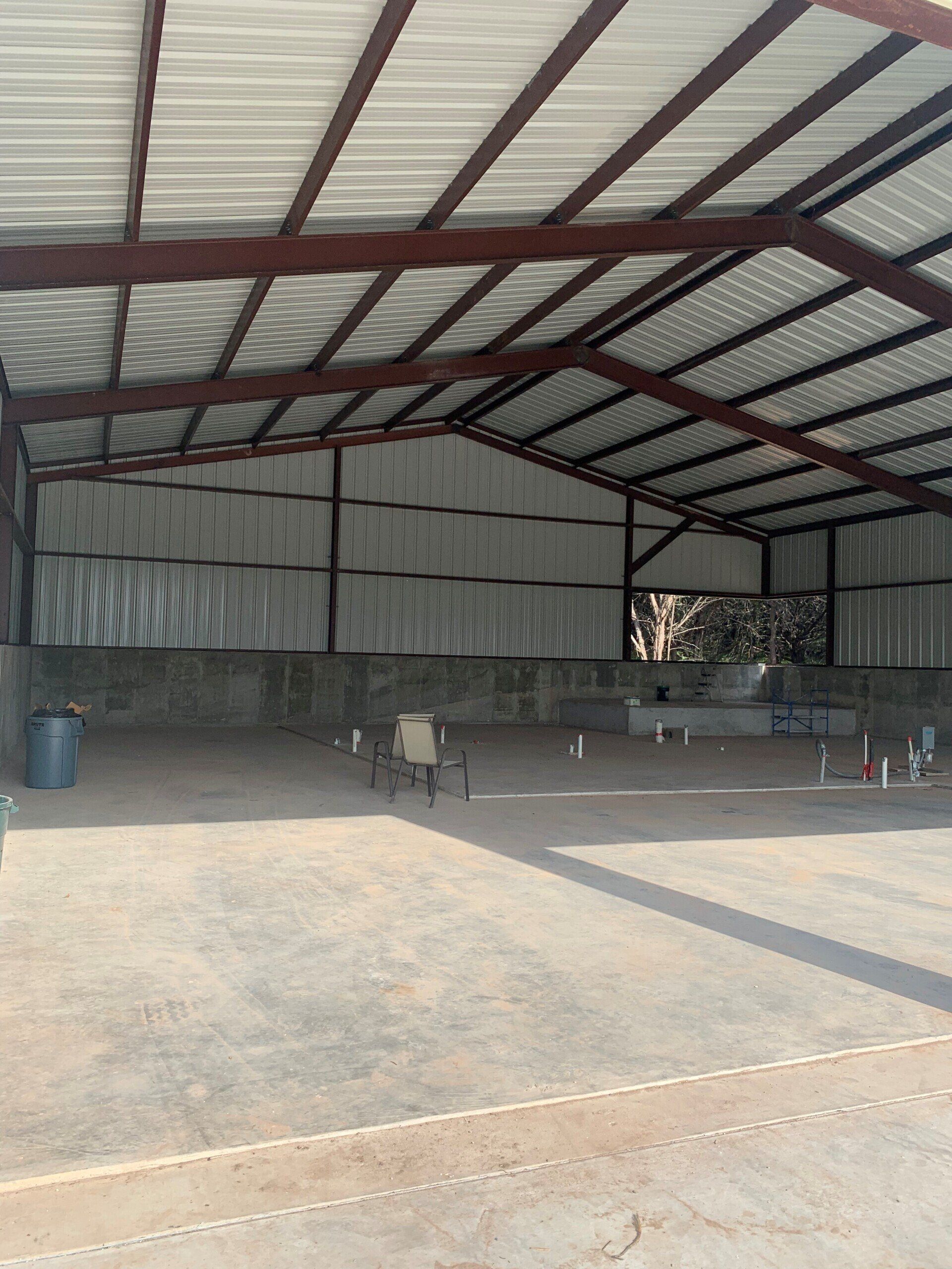 A large warehouse with a metal roof and a concrete floor.