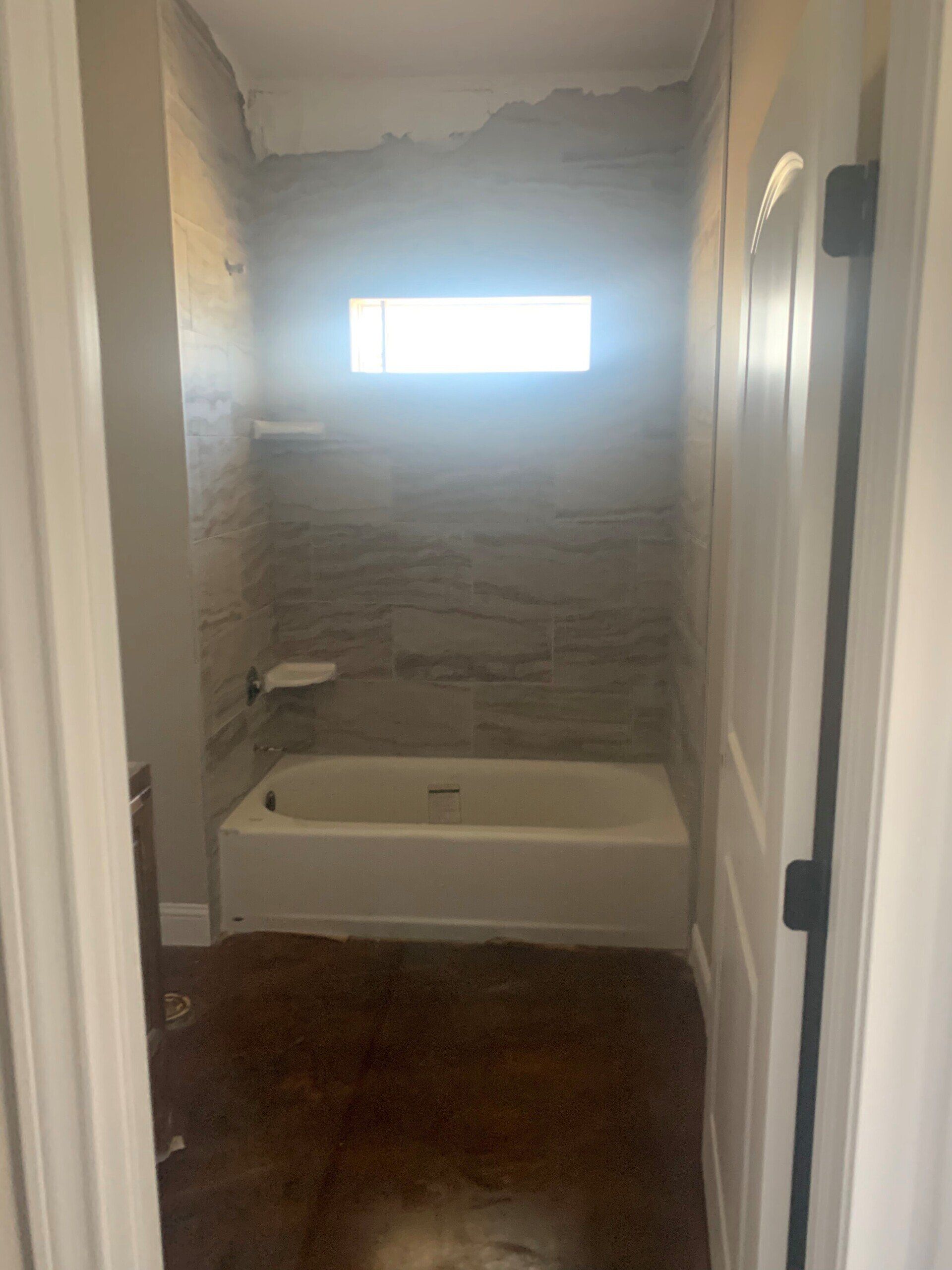 A bathroom with a bathtub and a window.