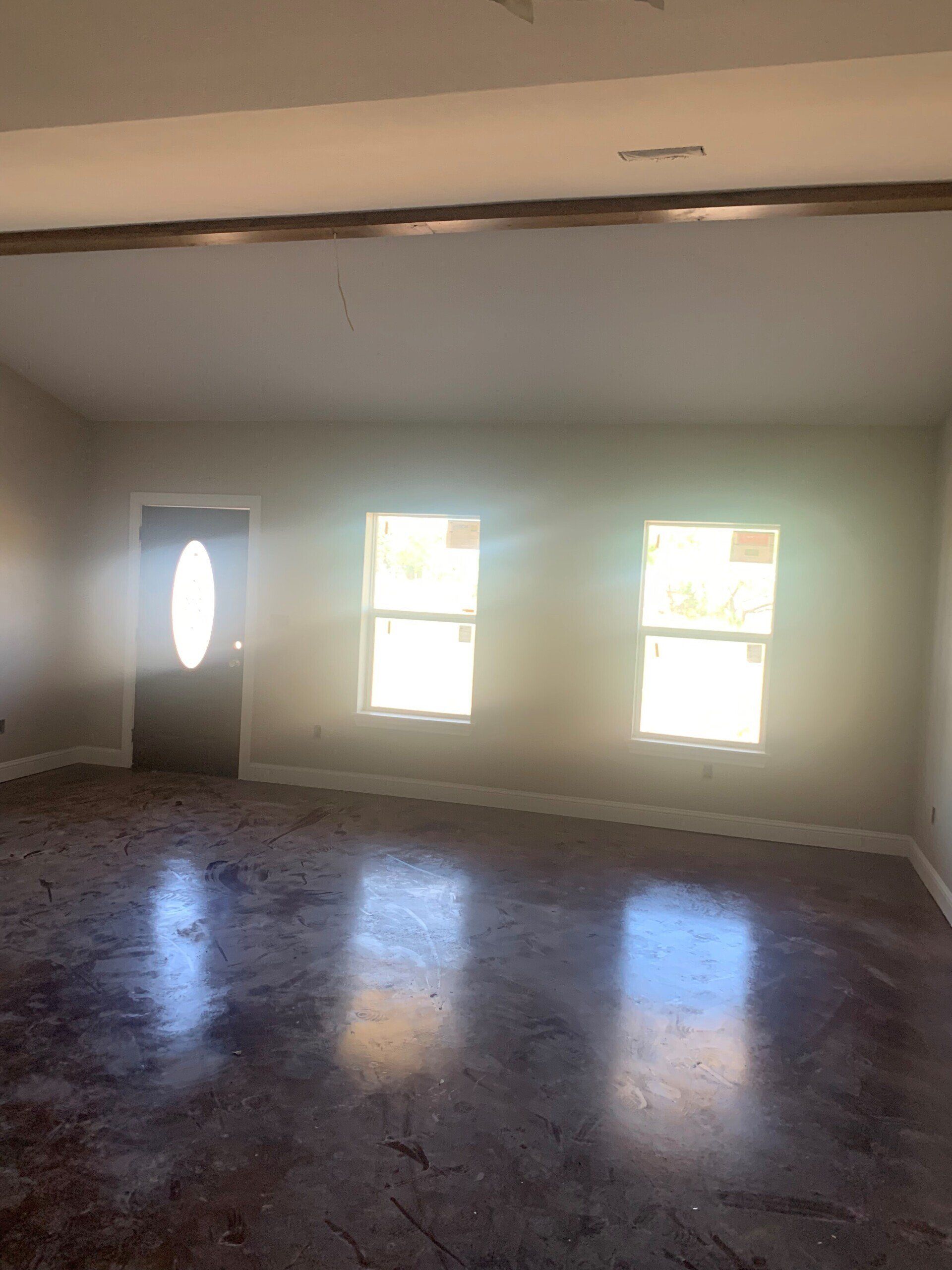 An empty living room with three windows and a door.