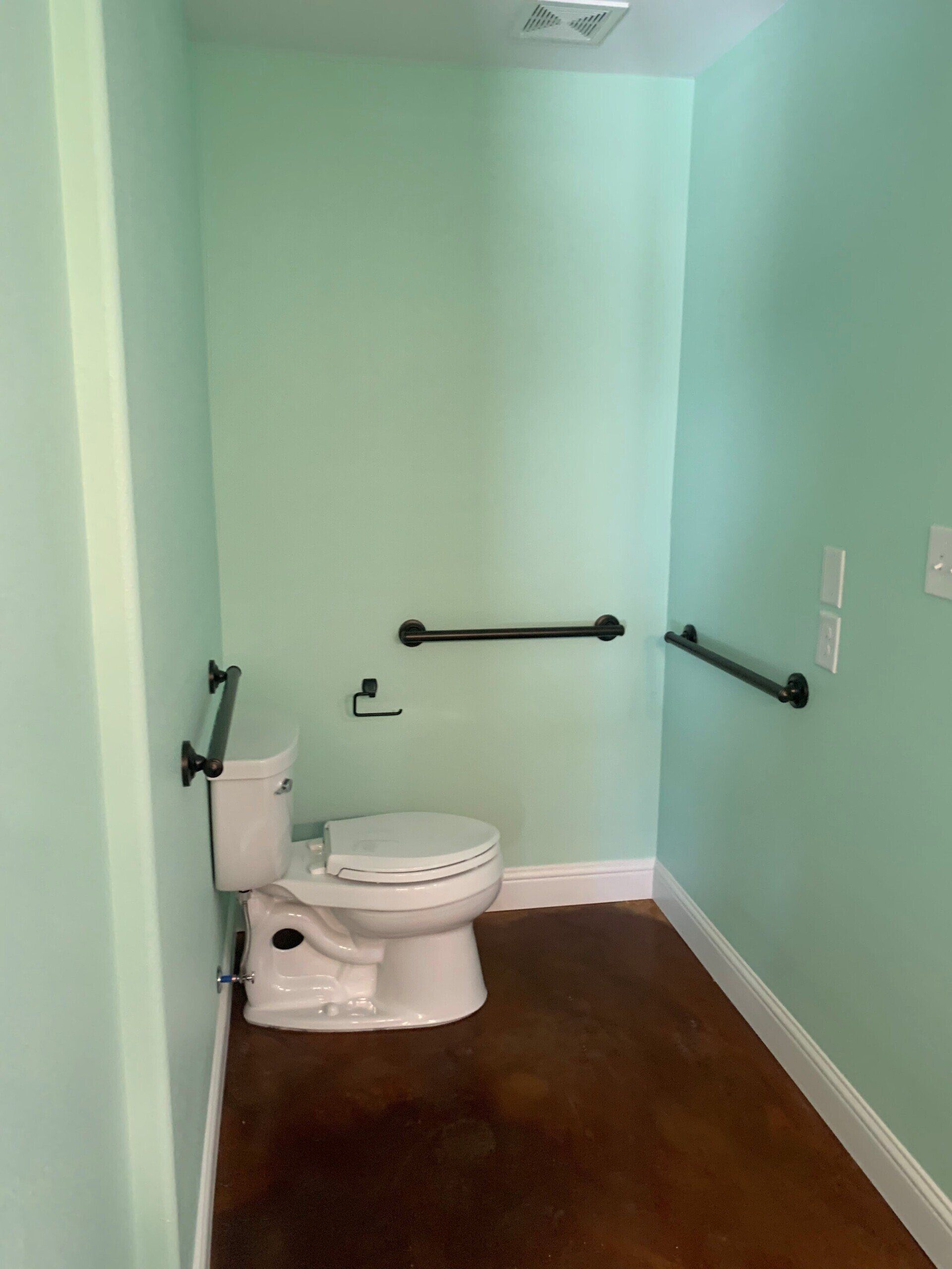 A bathroom with a toilet and handrails on the wall.