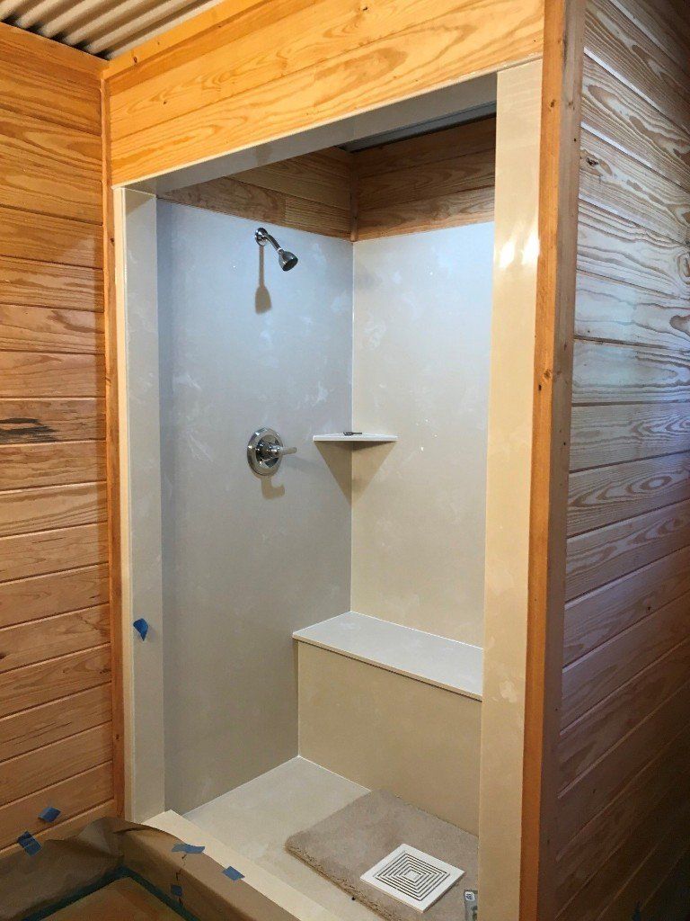 A shower with a bench and a shower head in a bathroom with wooden walls.