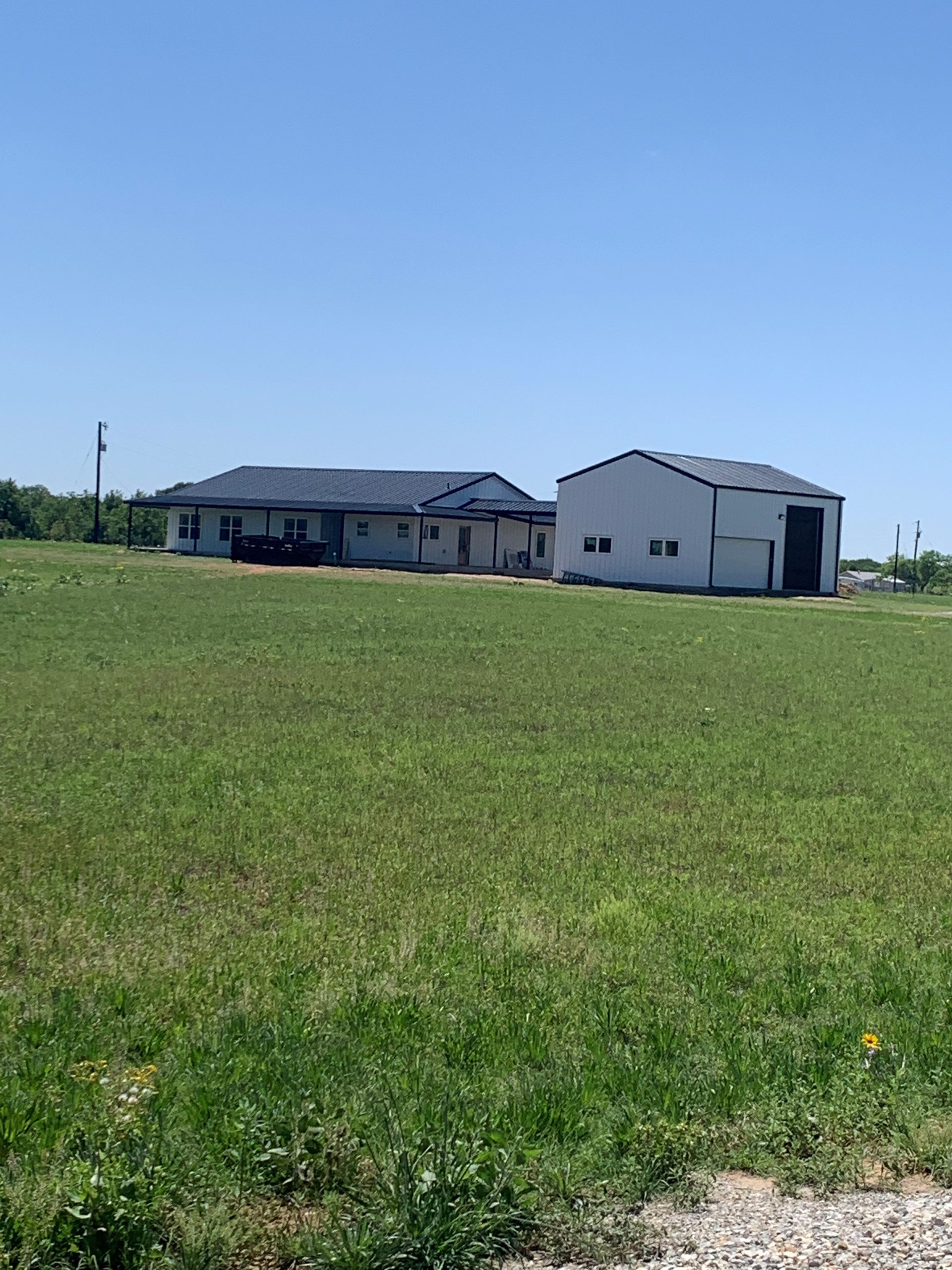 A large white house is sitting in the middle of a grassy field.