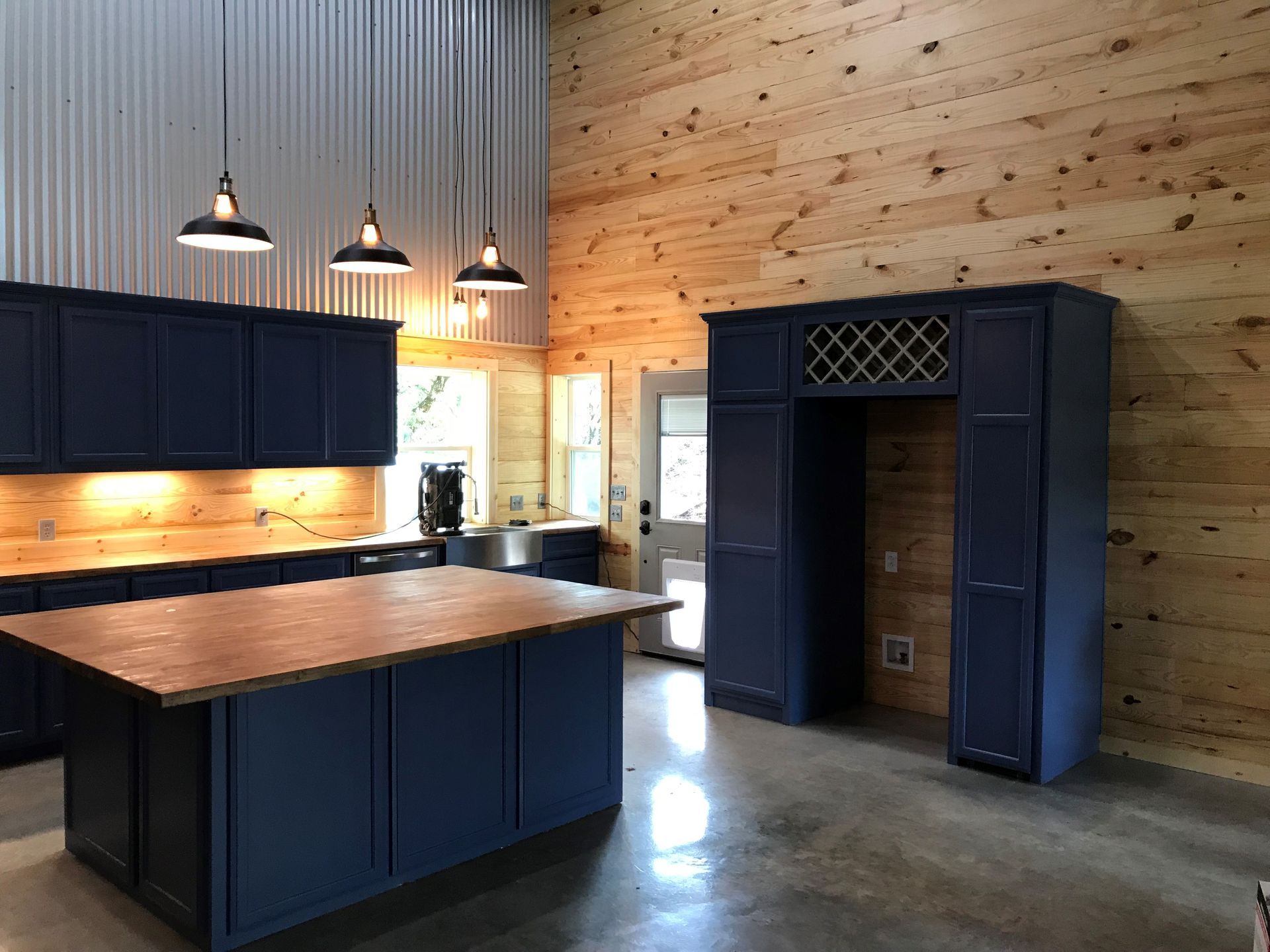 A kitchen with blue cabinets and wooden walls