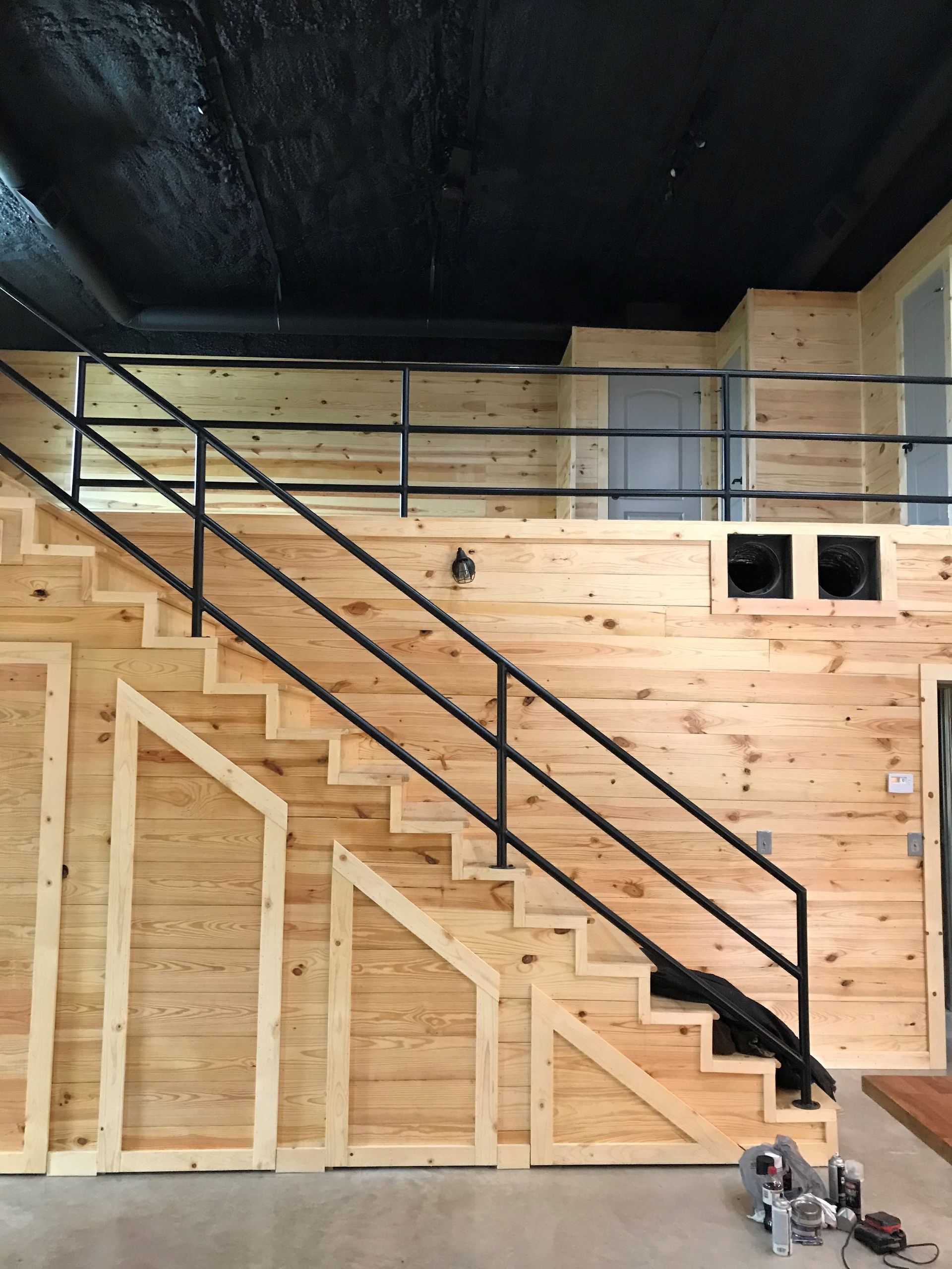 A wooden staircase with a metal railing in a room