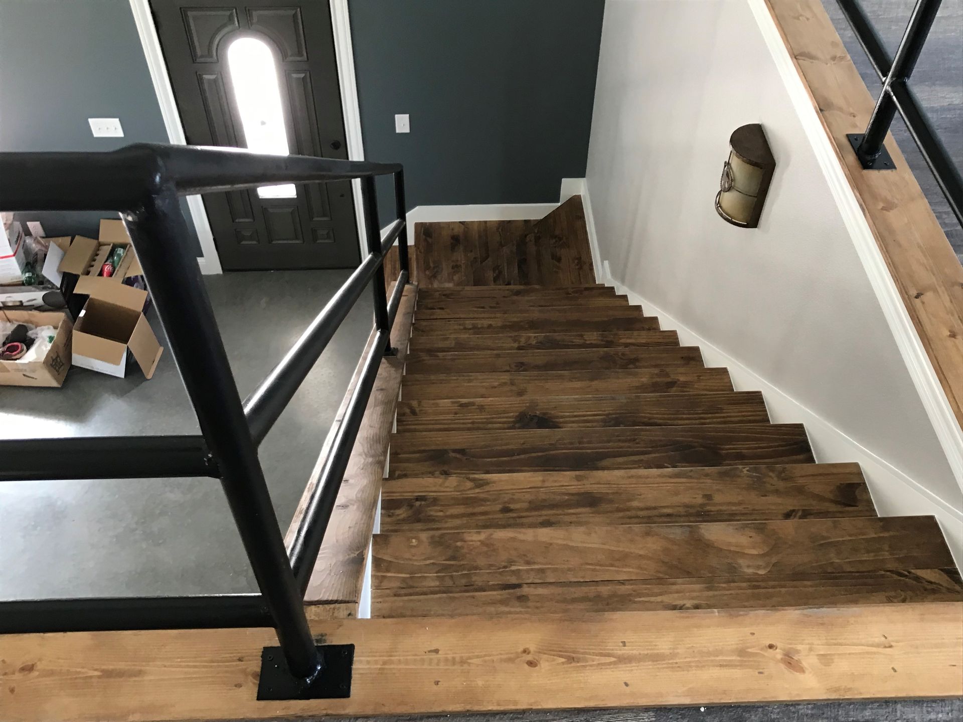 A wooden staircase with a black railing in a house.