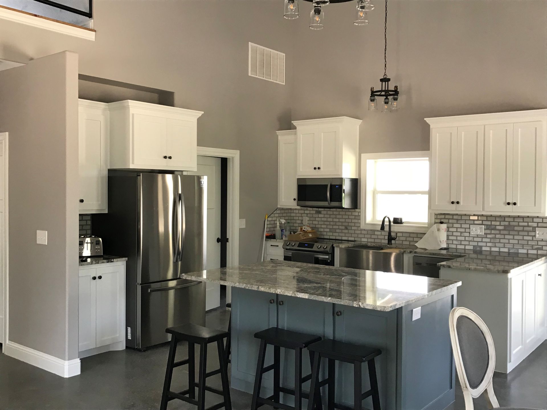 A kitchen with white cabinets , stainless steel appliances and a large island.